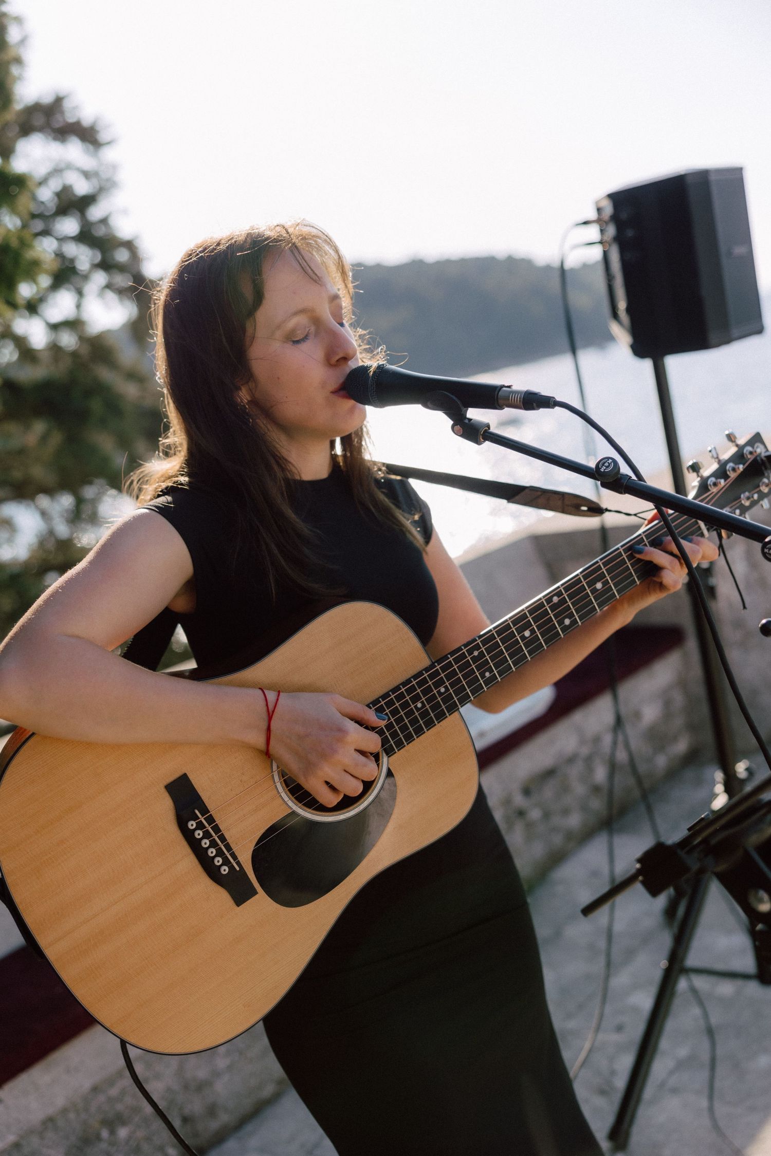 Musician performing on acoustic guitar at outdoor venue during sunset.