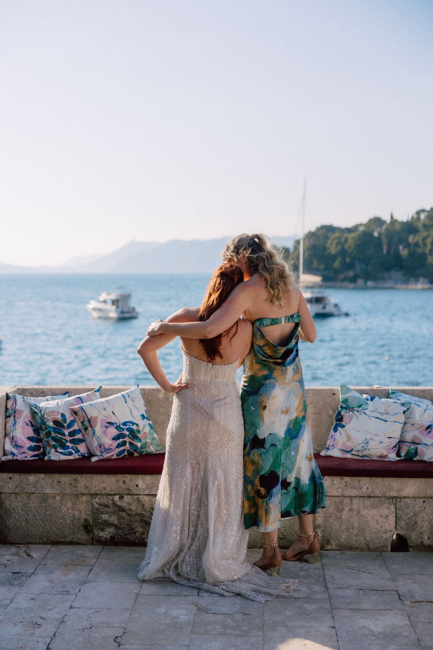 Group gathered along Mediterranean seaside wall with floral decorations and cushions.