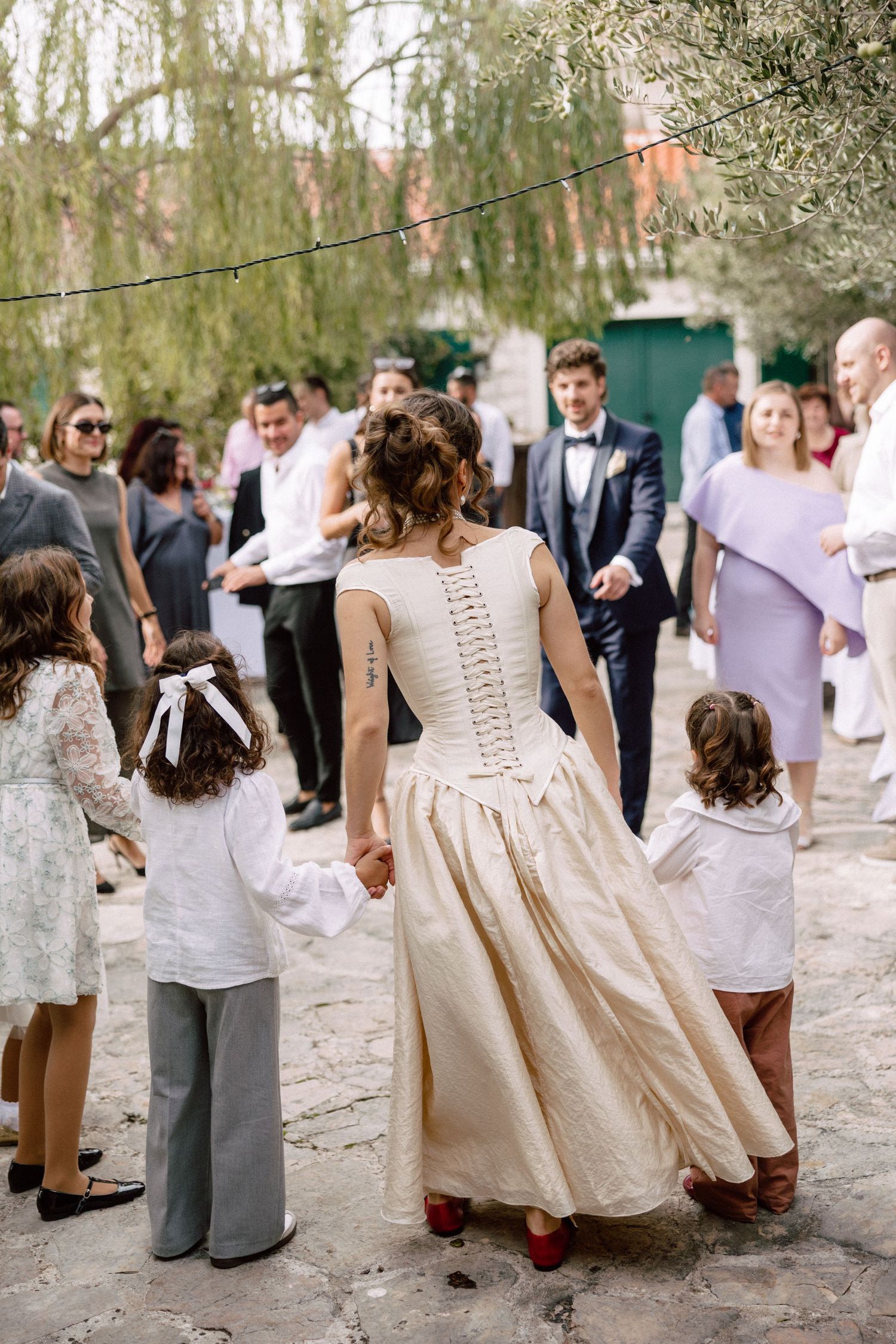 A group dances and celebrates at an outdoor wedding reception with a vintage-inspired dress featuring corset details.