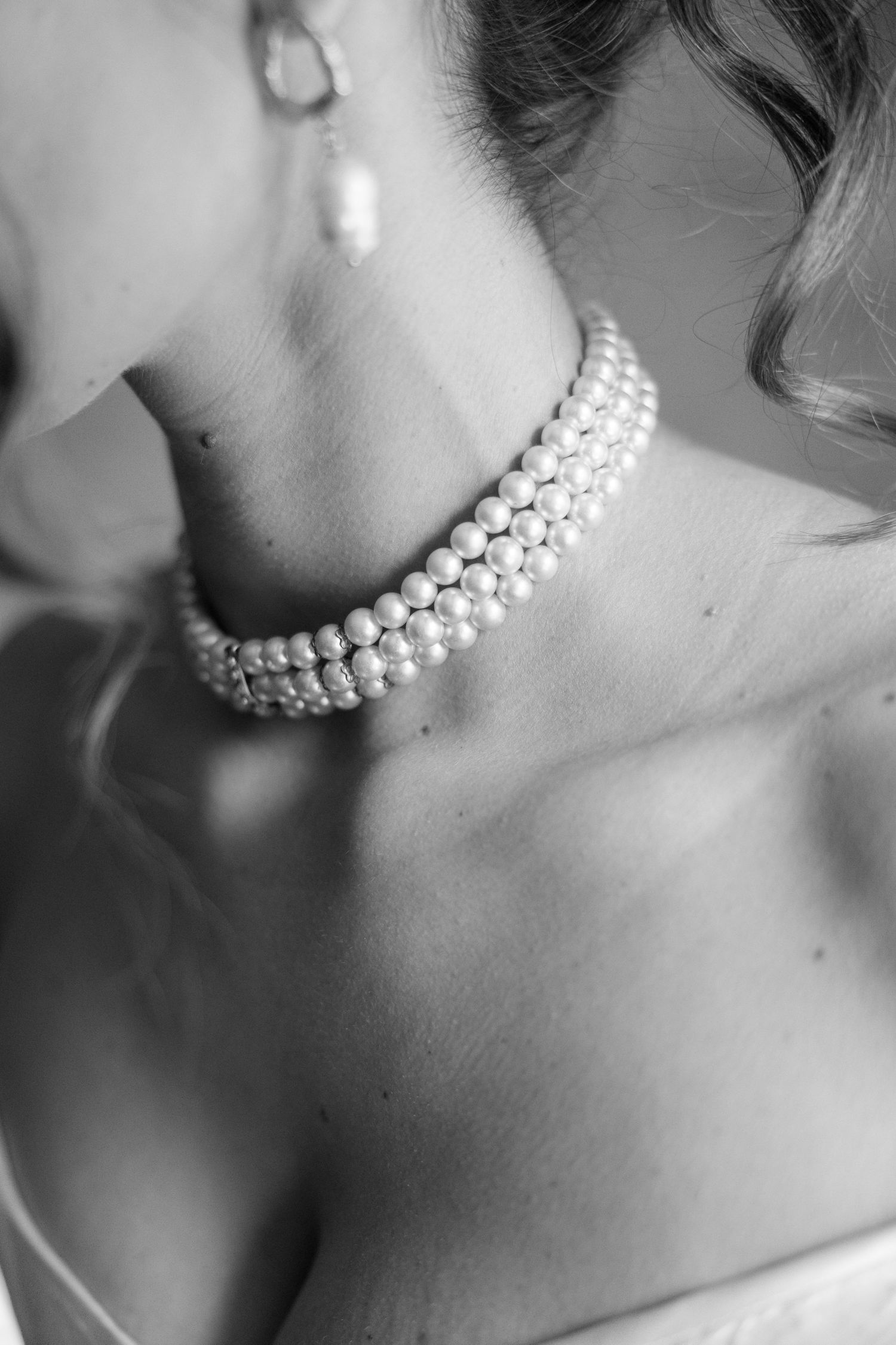 Close-up shots of an elegant pearl necklace adorning a neck in black and white photography.