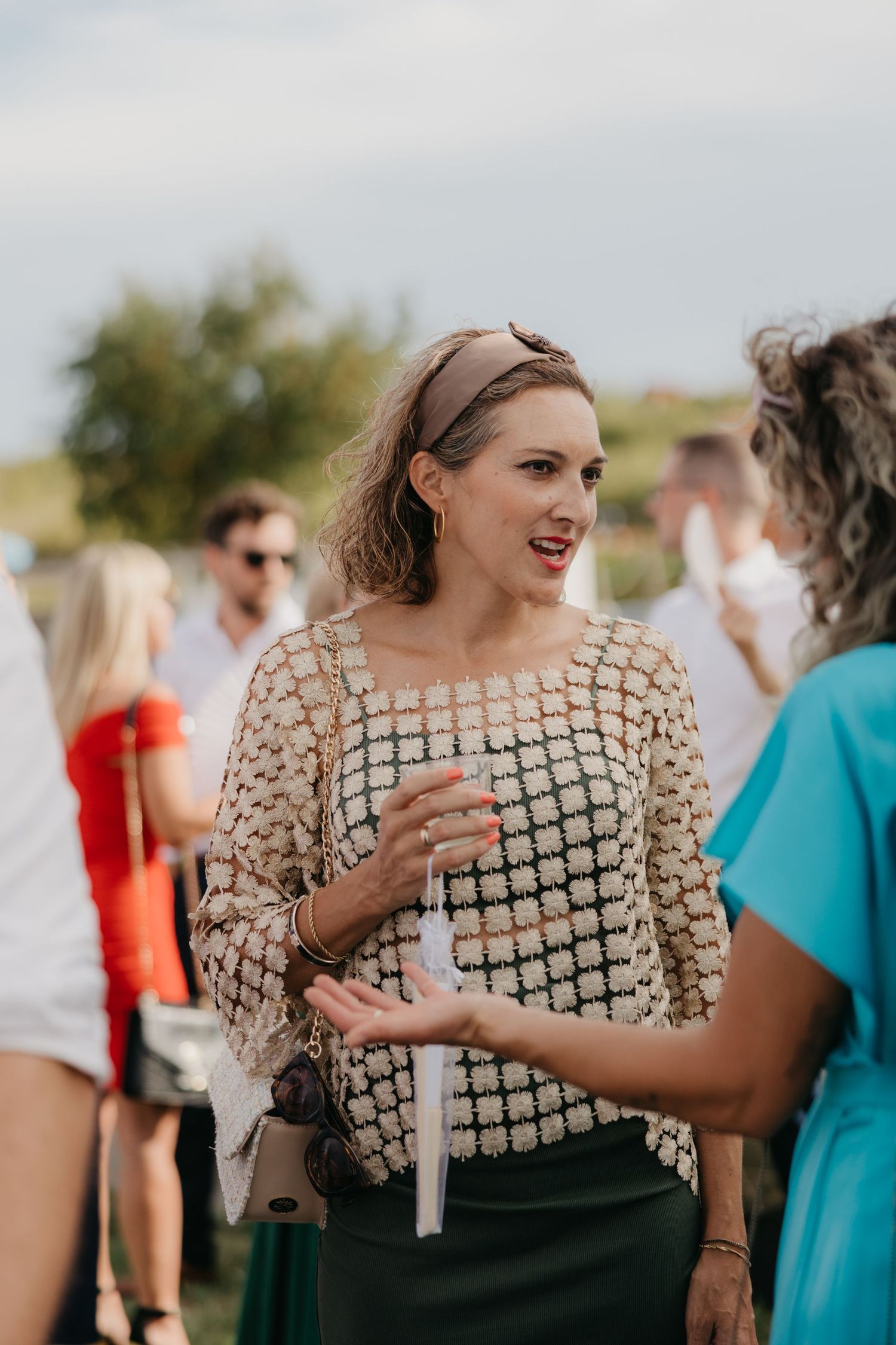 Woman in a sequined dress enjoying an outdoor celebration.