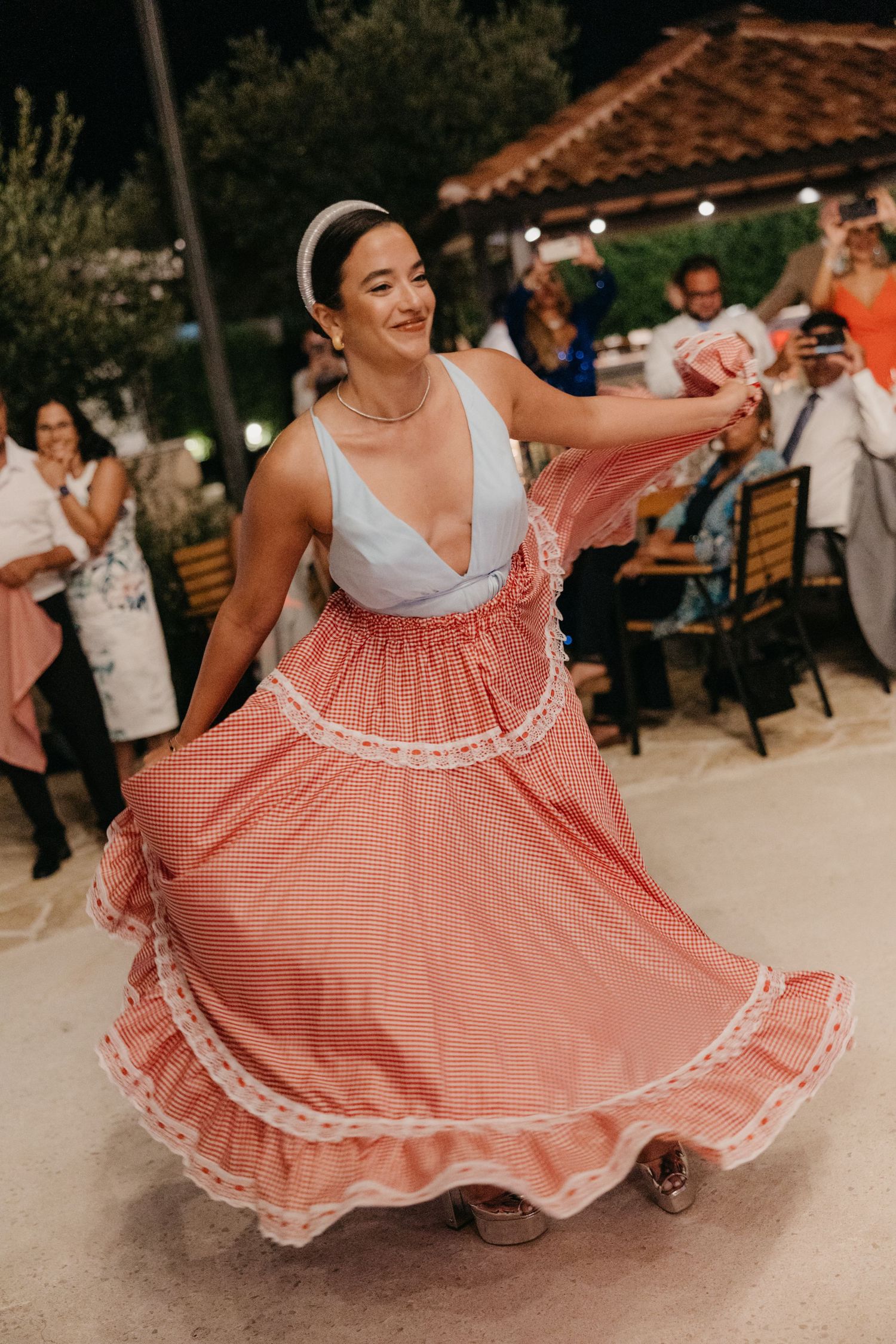Dancer twirls in pink traditional dress with white lace trim at outdoor celebration.