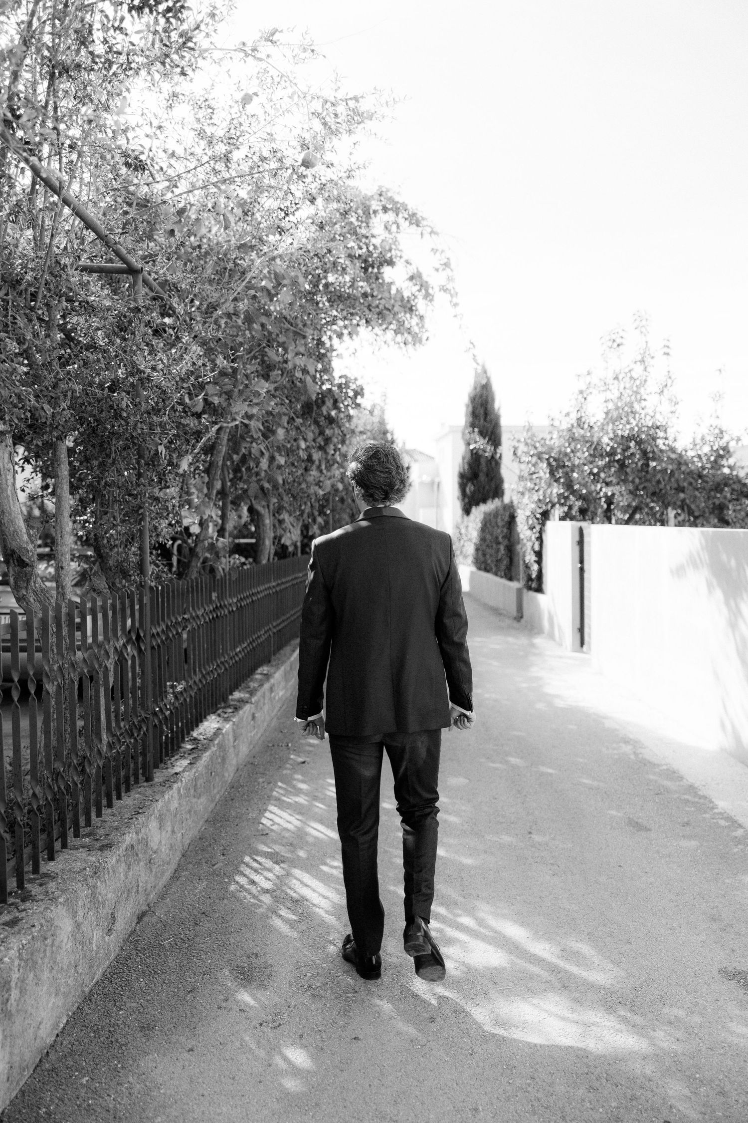 Black and white photo of people walking down a tree-lined path.