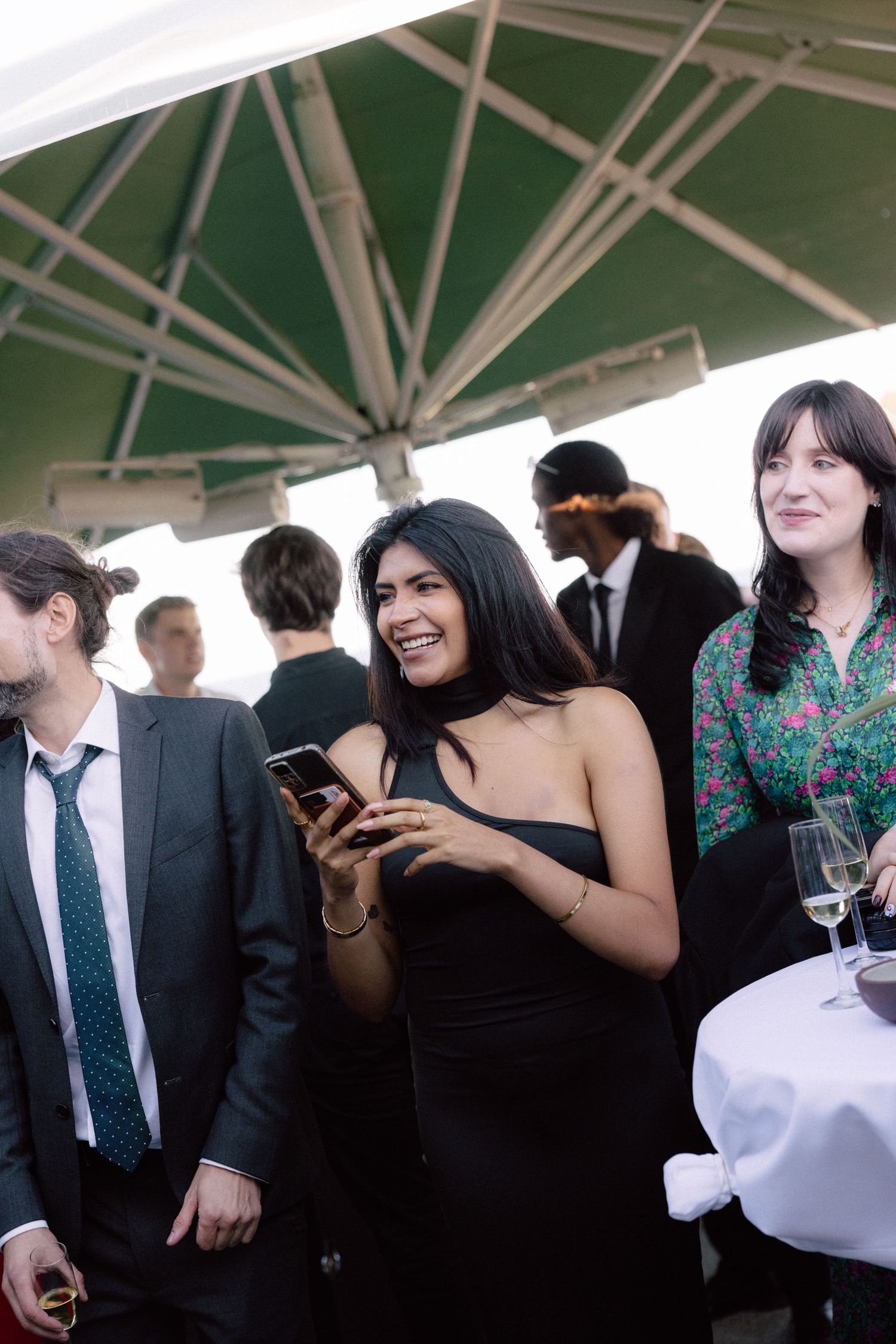 Wedding guests mingle and socialize under an outdoor tent during the reception.