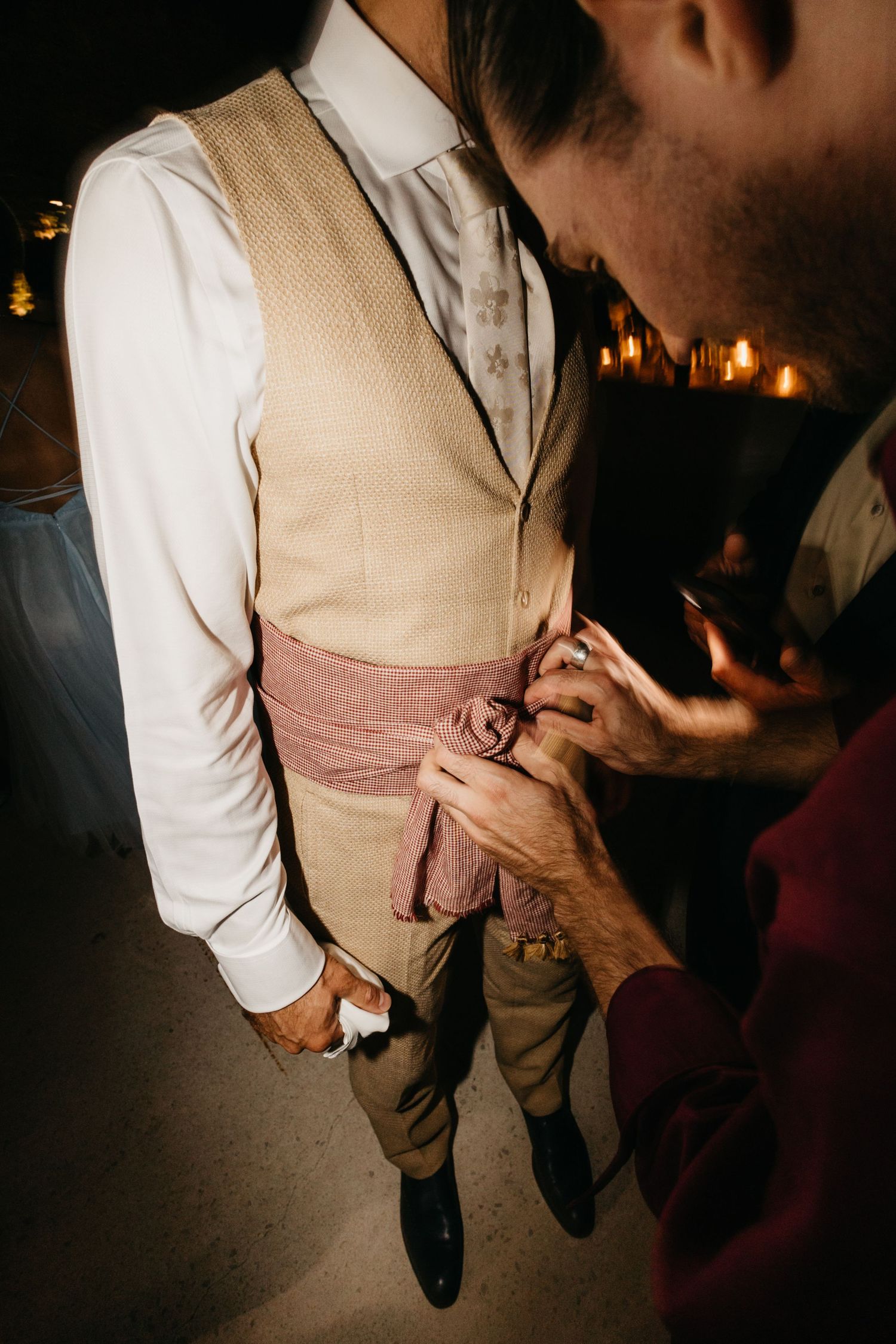 Formal attire at a wedding showing tan vest and white shirt details in low light.