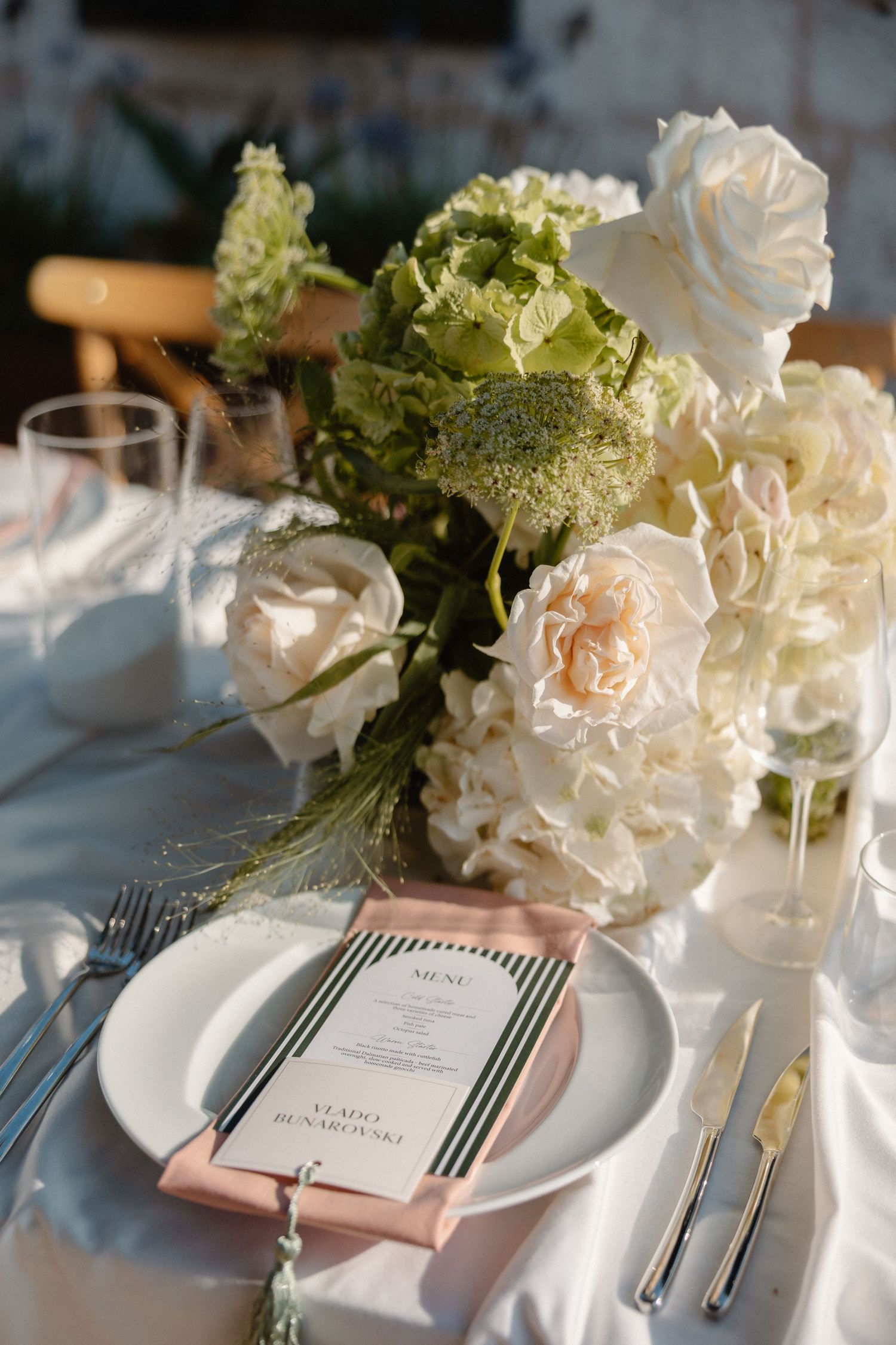 Elegant wedding table setting with white roses, hydrangeas, and personalized menu card.
