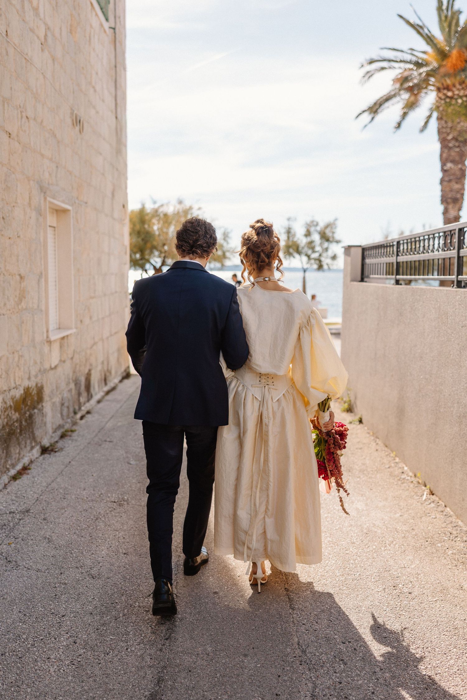 Couple walking along a white stone pathway with palm trees in the background.