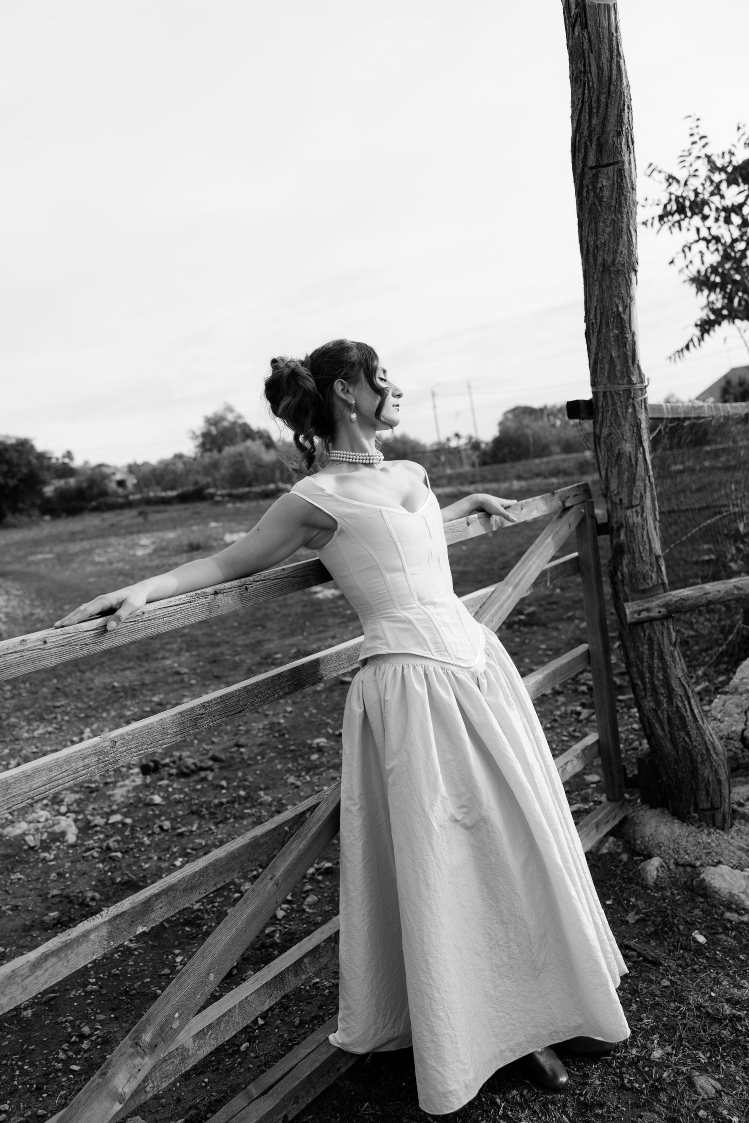 A flowing white dress twirls gracefully in a black and white outdoor portrait.