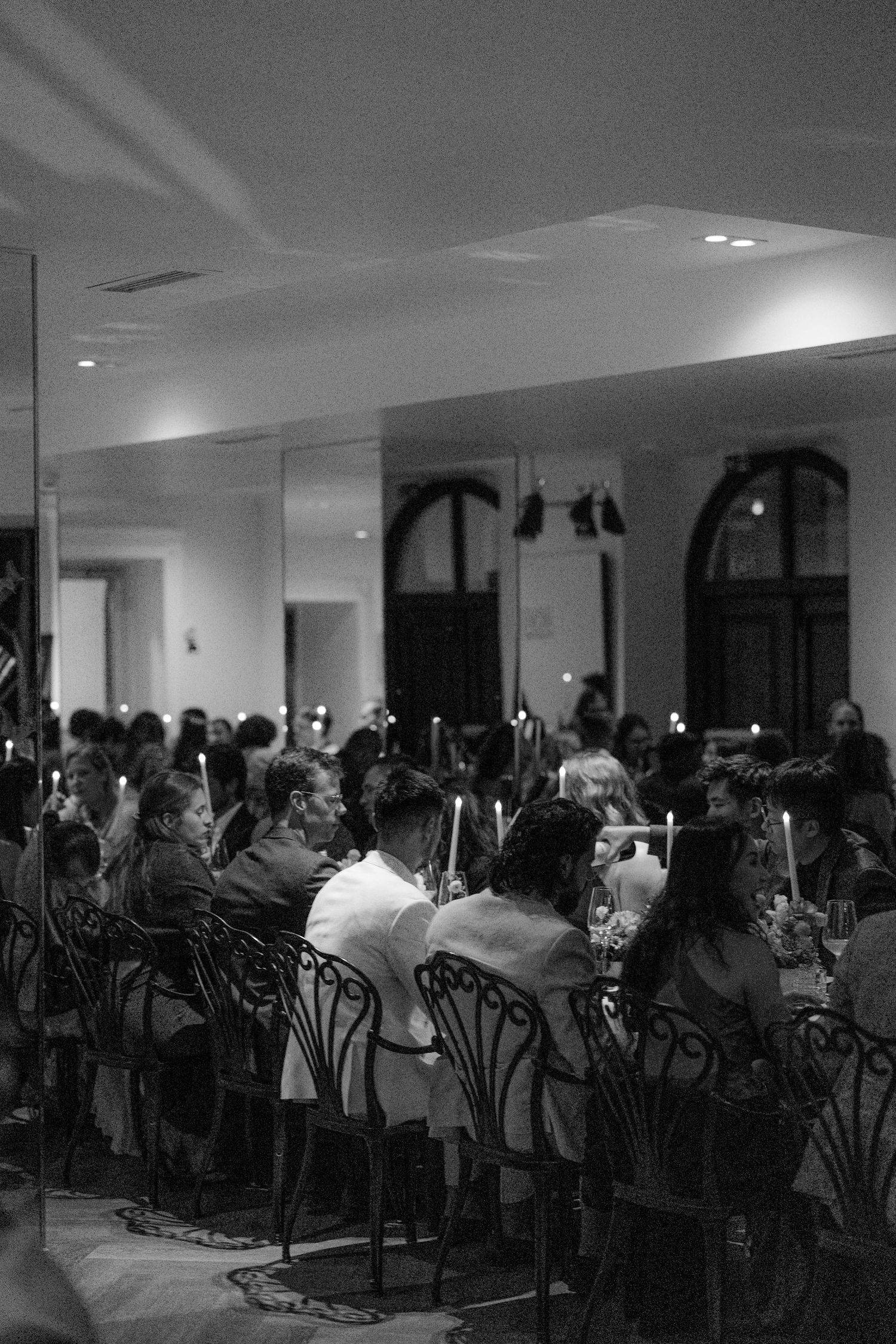 Wedding reception dinner guests seated at candlelit tables in elegant venue.