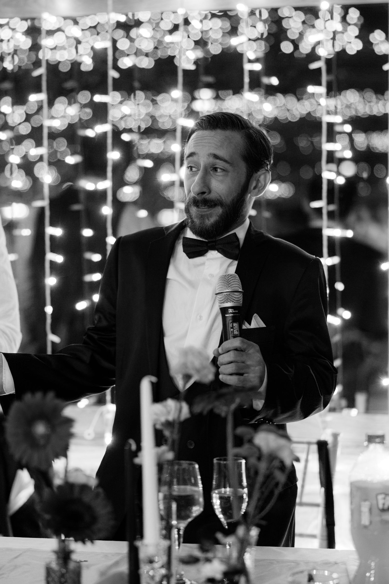 A wedding speech being given under romantic string light decorations.