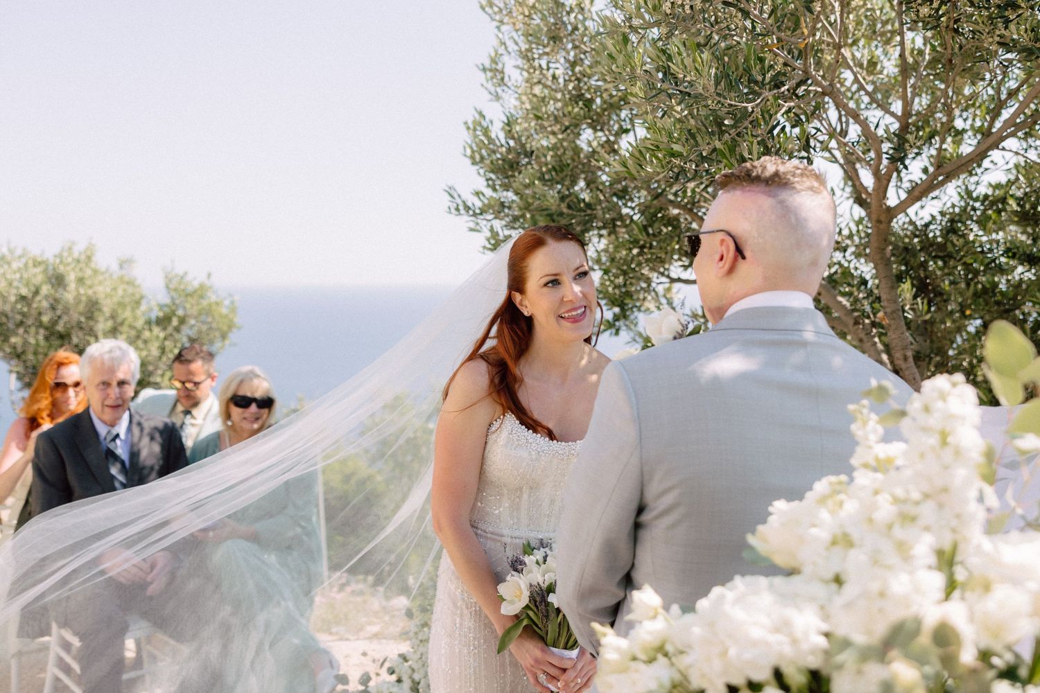 Wedding ceremony setup outdoors with white floral decorations and mountain backdrop.