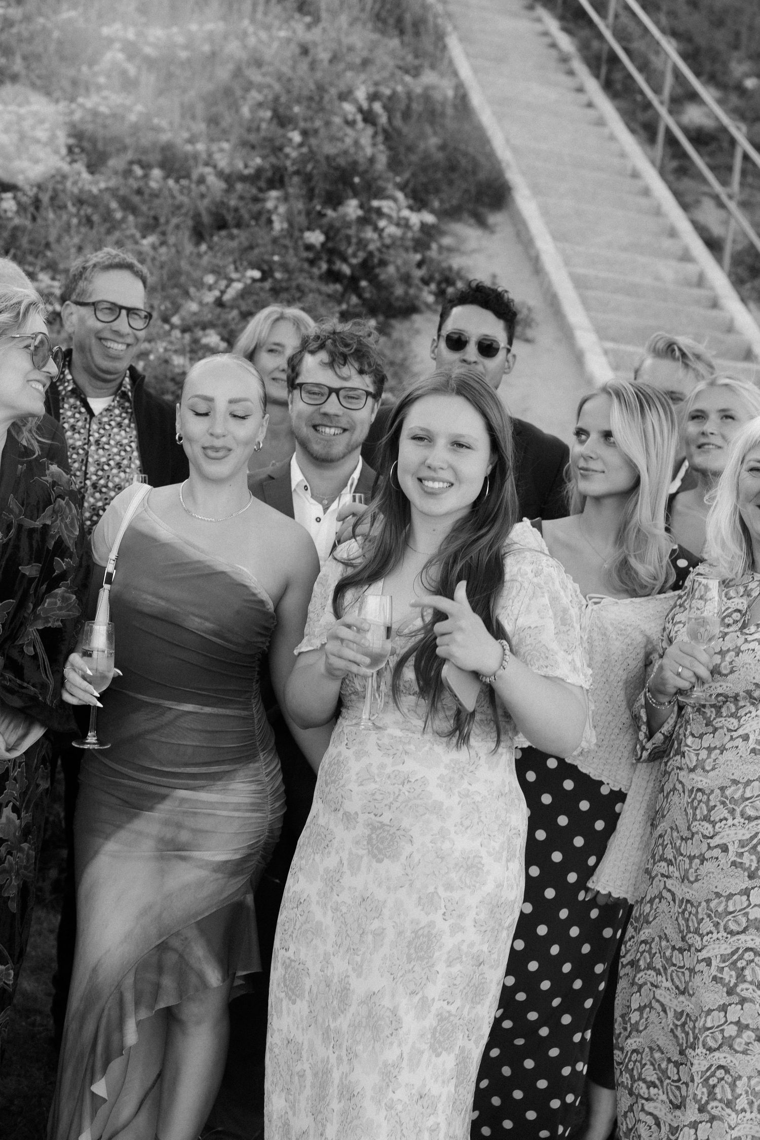 Festive group of wedding guests in formal attire enjoying themselves outdoors.