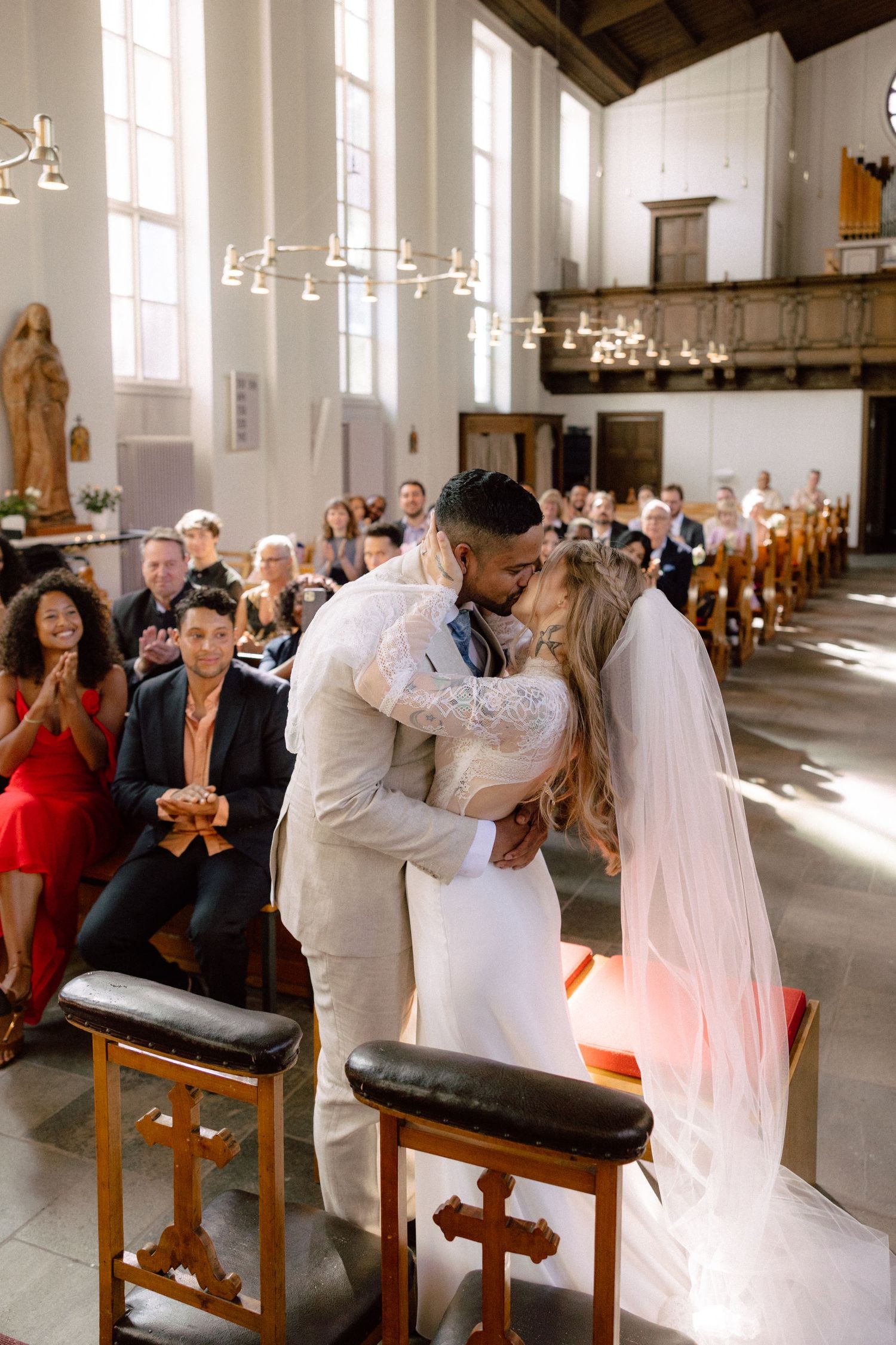 Newlyweds share their first kiss in church as wedding guests applaud.