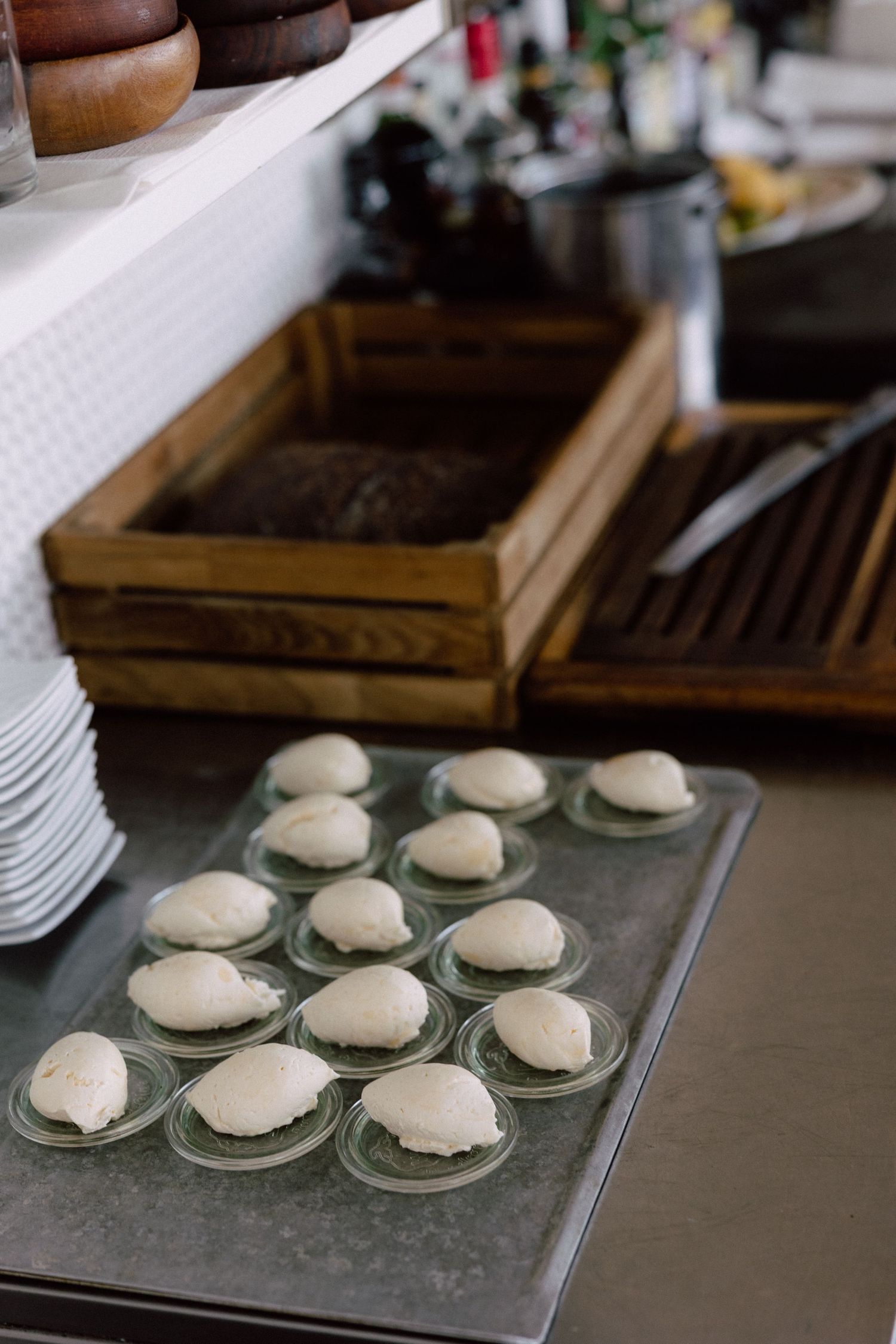 White cream-filled pastries arranged on a metal tray with wooden boxes in background.