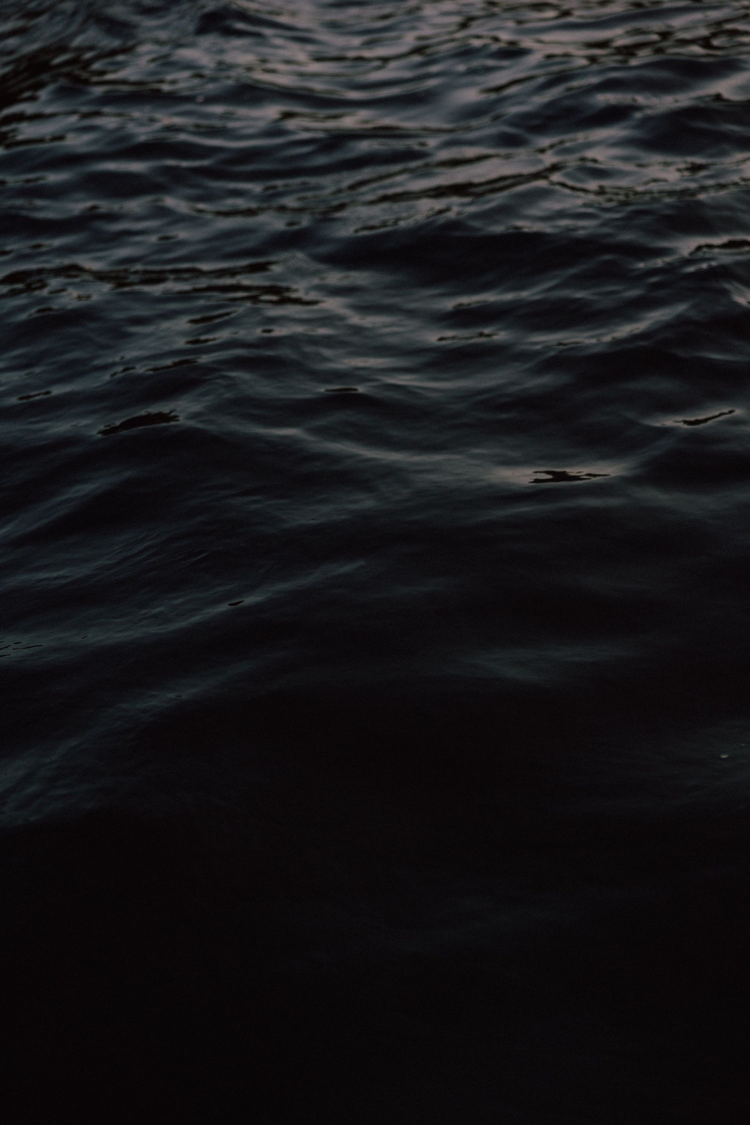 Dark rippling ocean water with gentle waves creating abstract patterns.