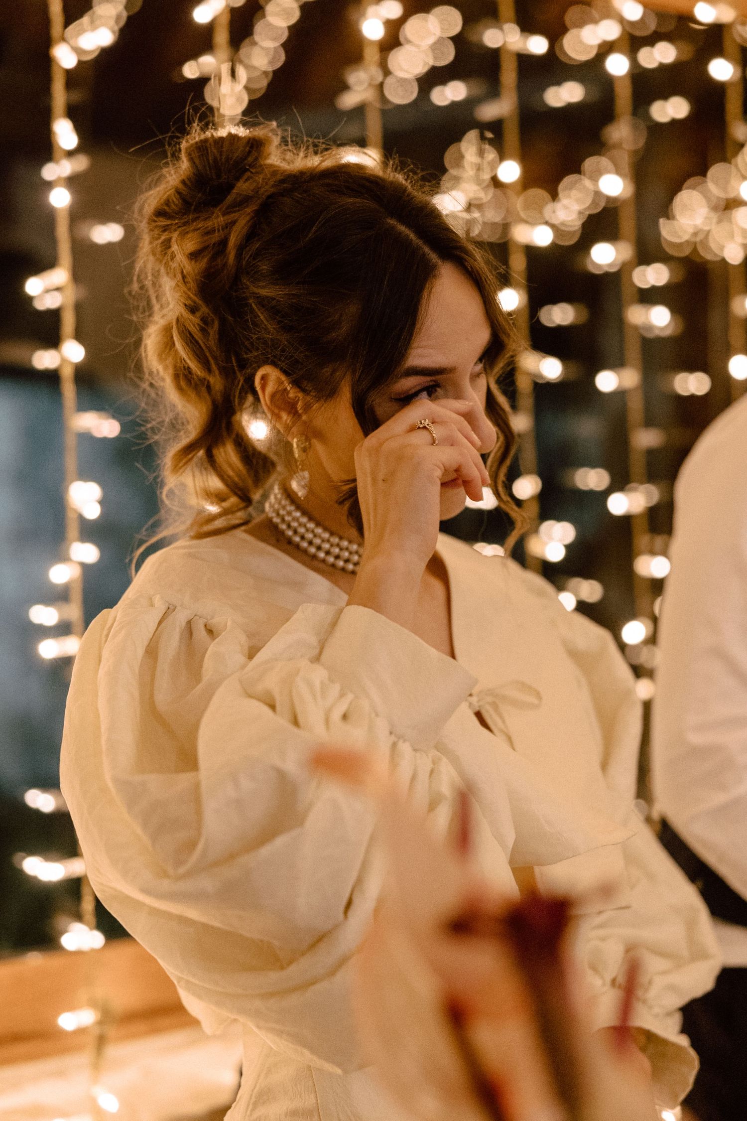 Bride in classic white dress dancing under warm twinkle lights in an intimate setting.