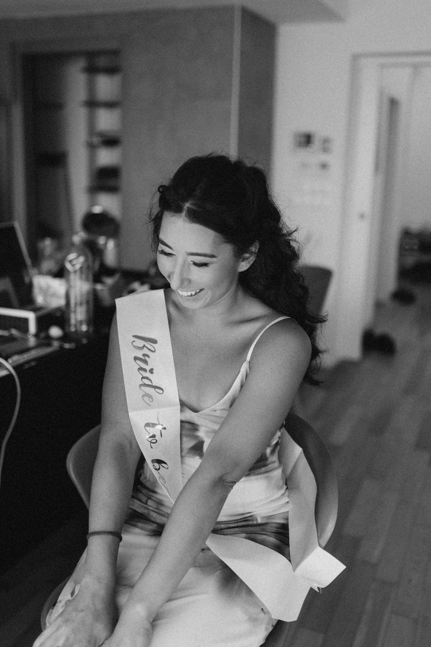 Joyful candid moment during wedding preparations in black and white.