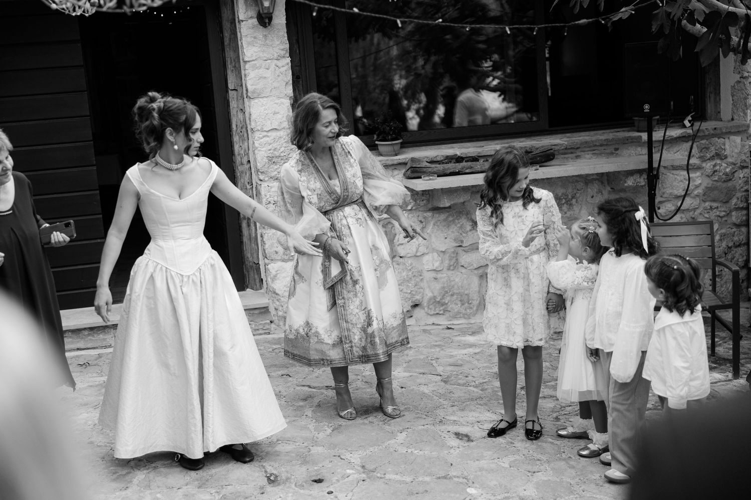 Black and white outdoor wedding scene with guests gathered in casual celebration.