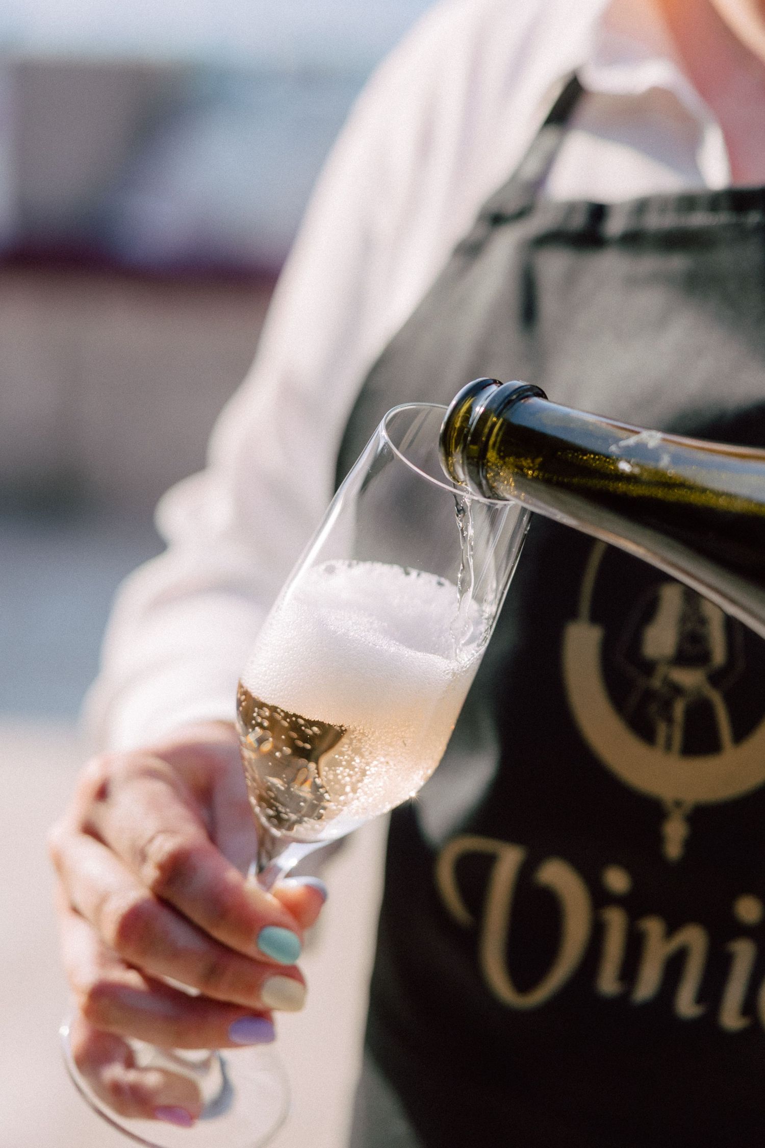 Champagne being poured into elegant glasses at outdoor event.