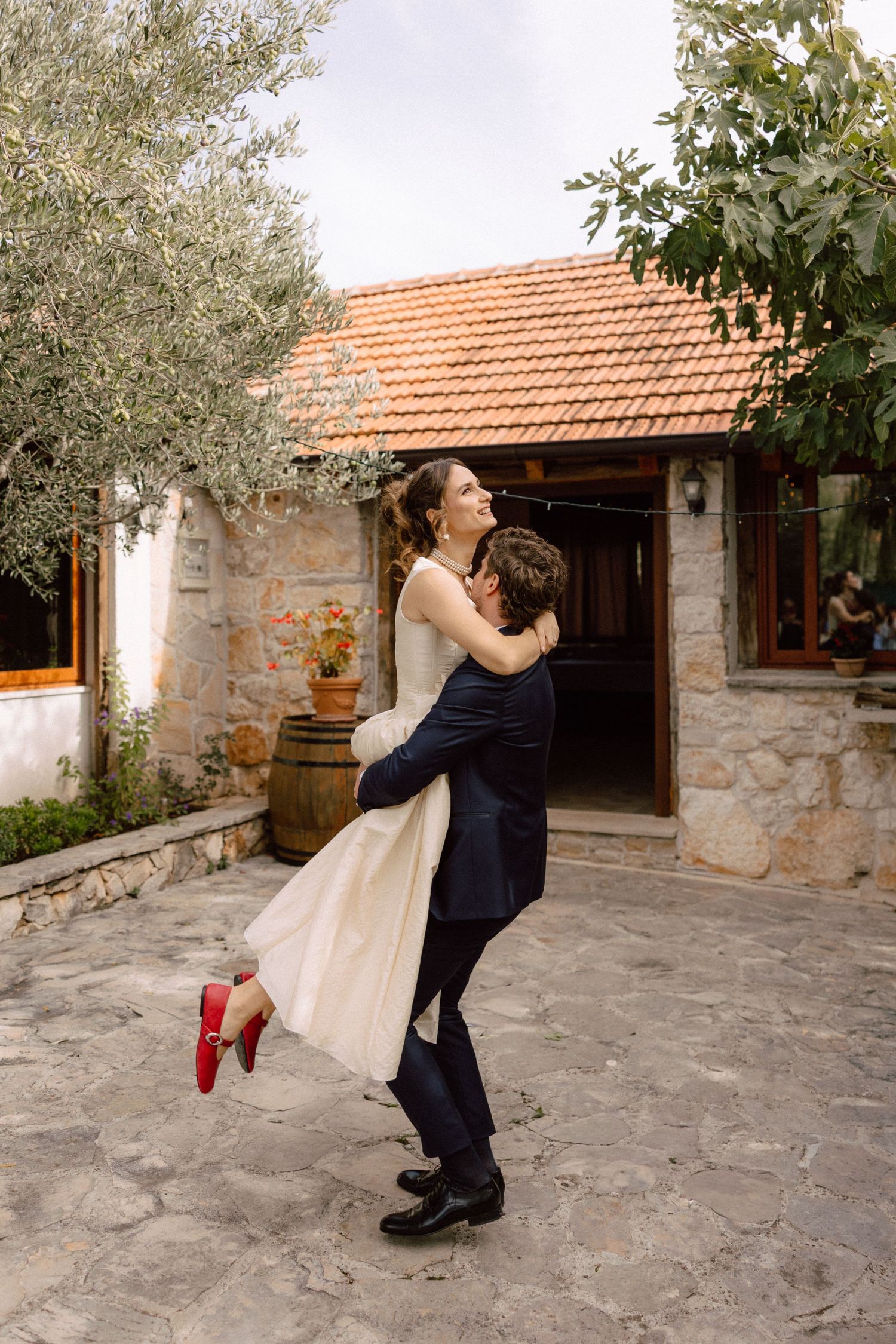 Dancing couple in formal attire spinning in a rustic stone courtyard.