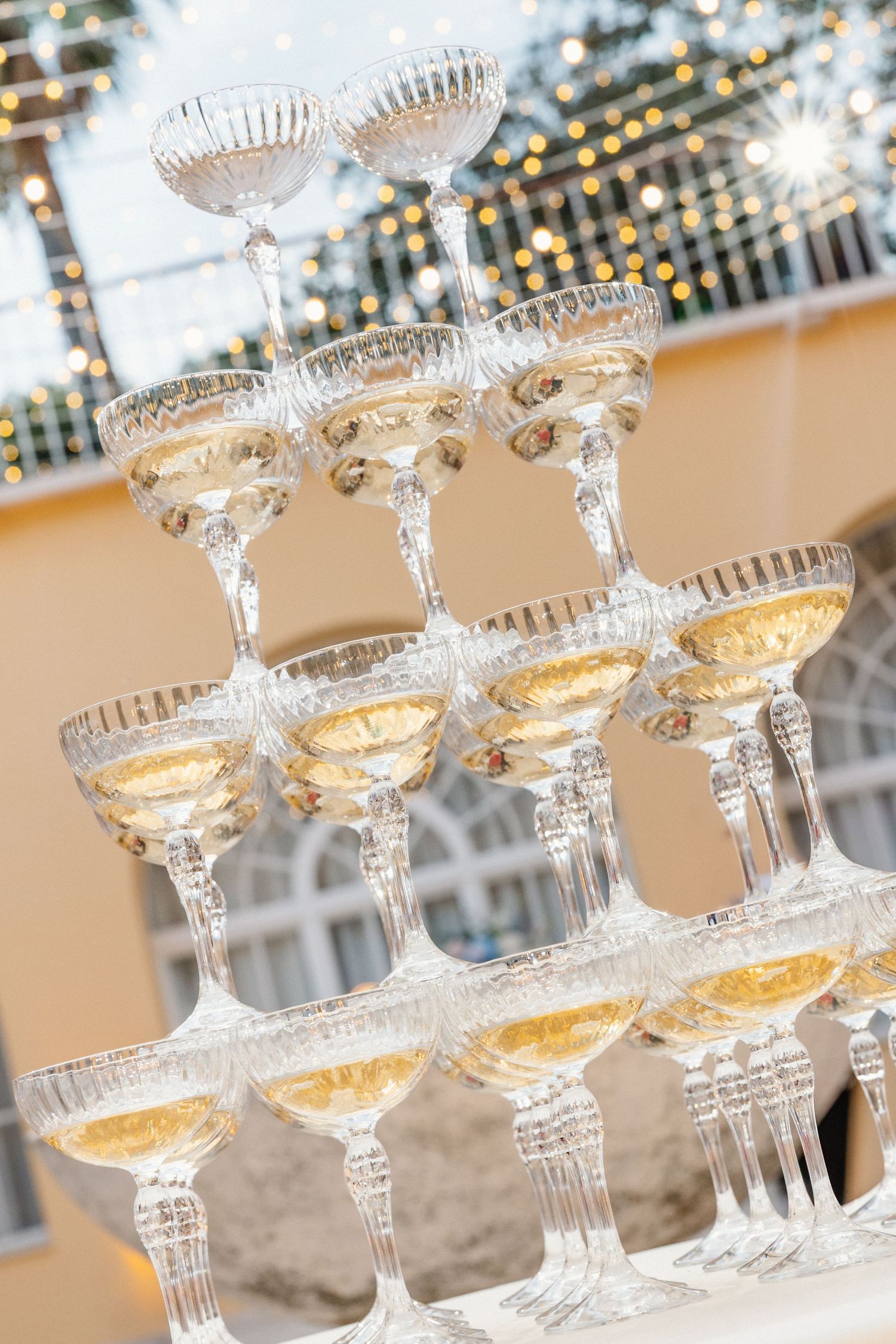 Elegant crystal champagne coupe glasses arranged in a tower display with golden bubbly liquid.