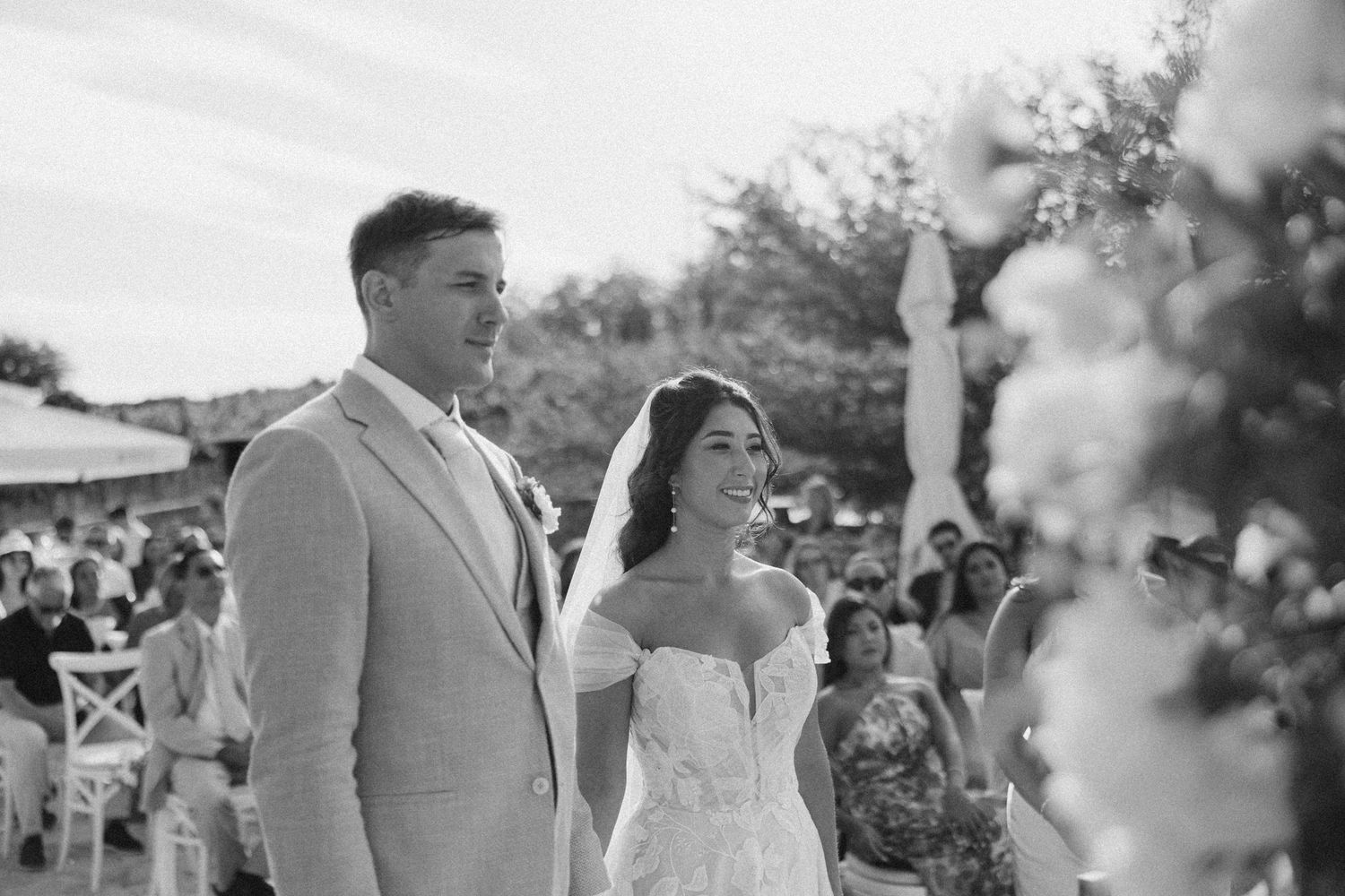 Black and white photo capturing an intimate wedding ceremony moment outdoors.