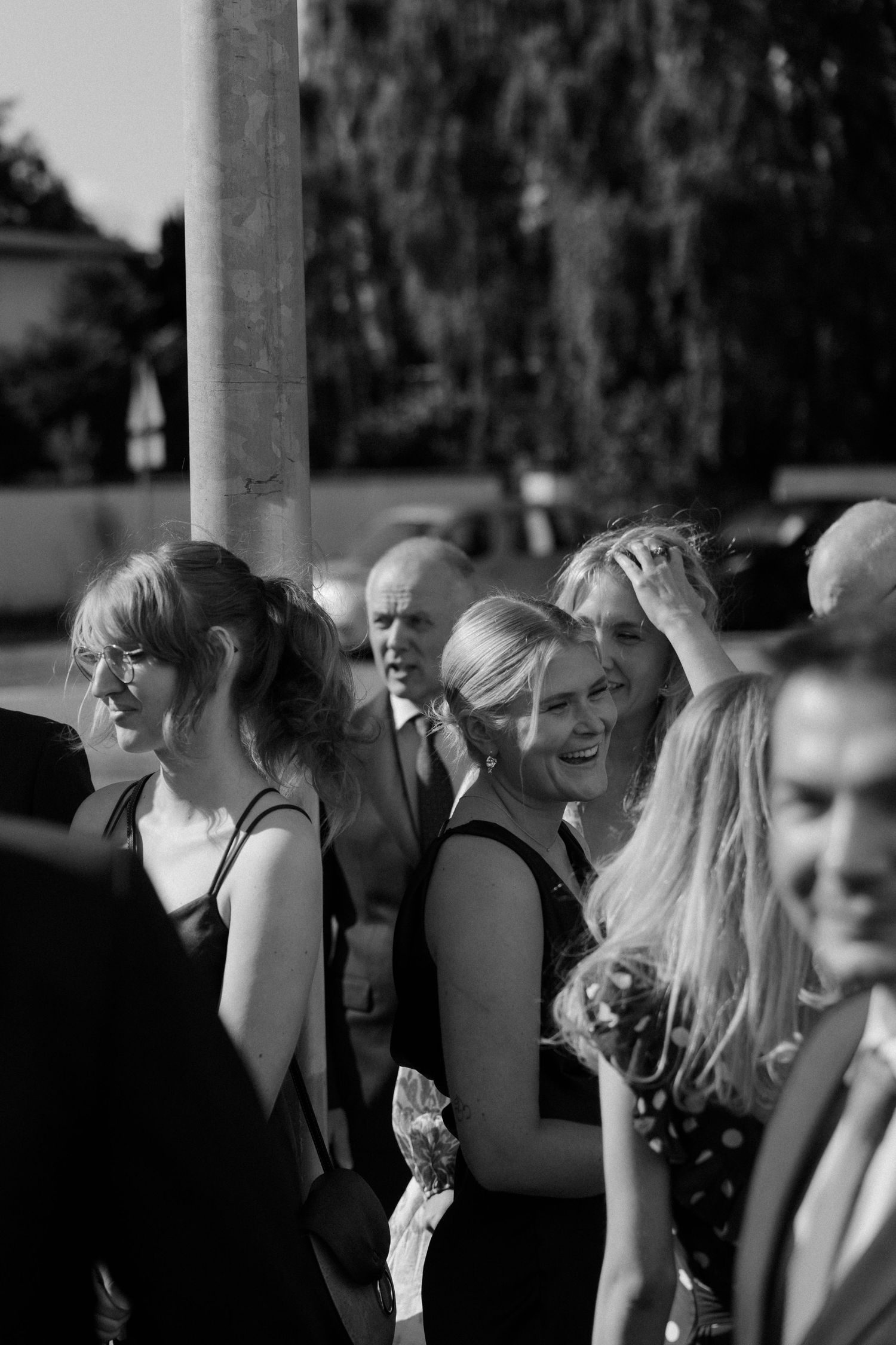 Black and white photo of wedding guests enjoying themselves at outdoor reception.