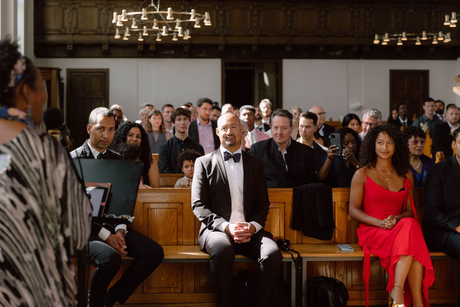 Wedding guests smile and laugh in church pews during a joyful ceremony.
