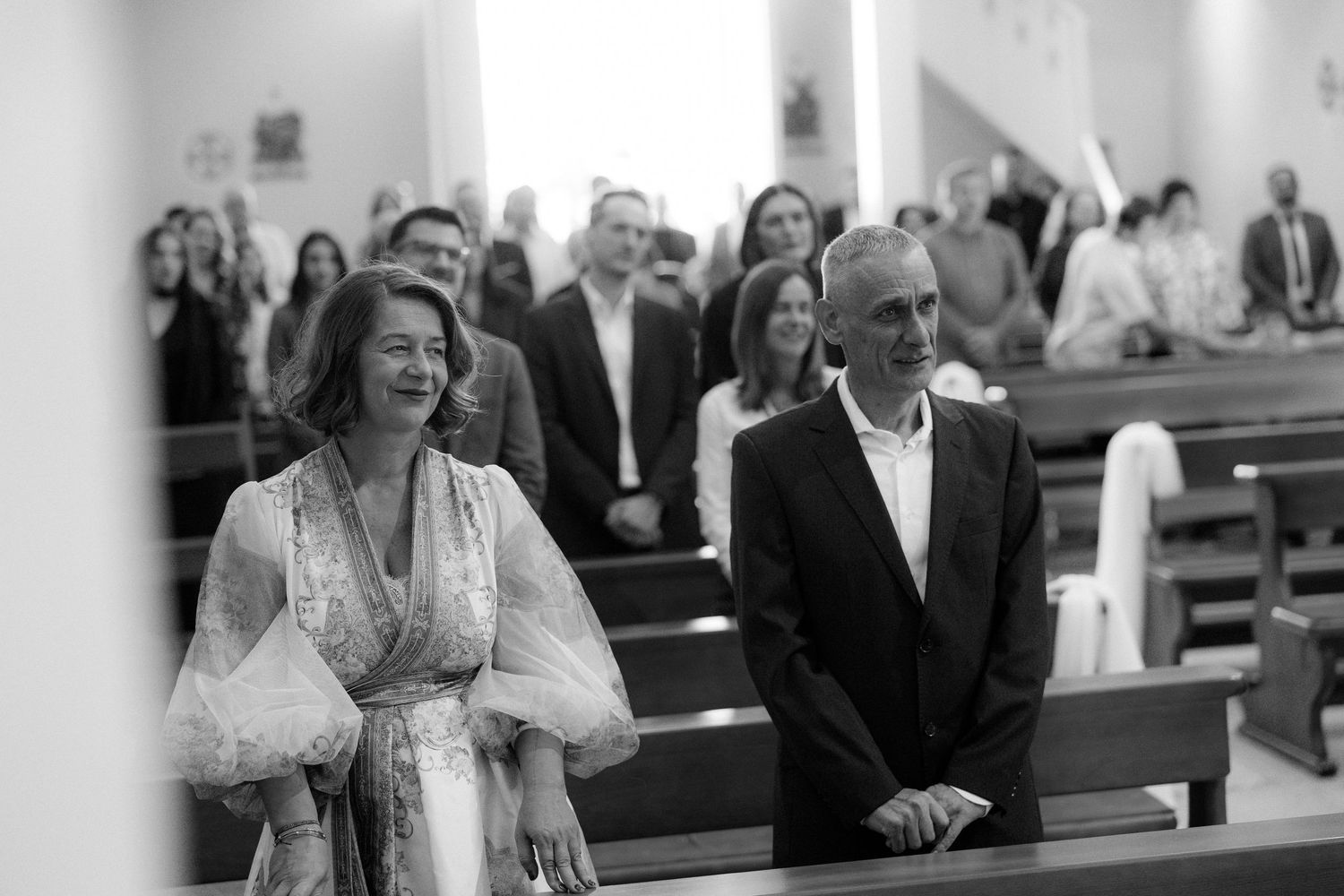 Wedding guests seated in church pews during ceremony.