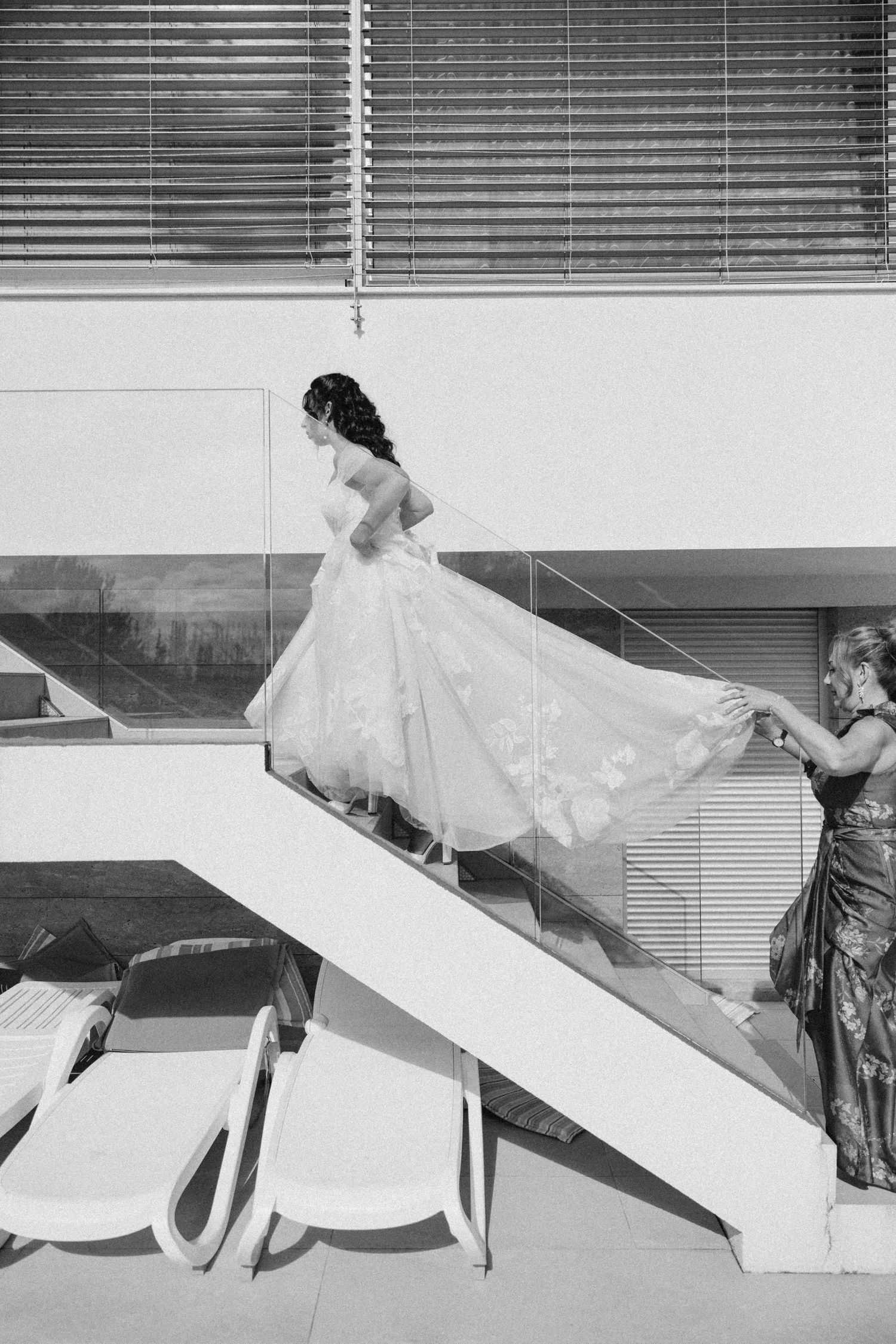 Artistic black and white photo of a bride walking down modern architectural steps.