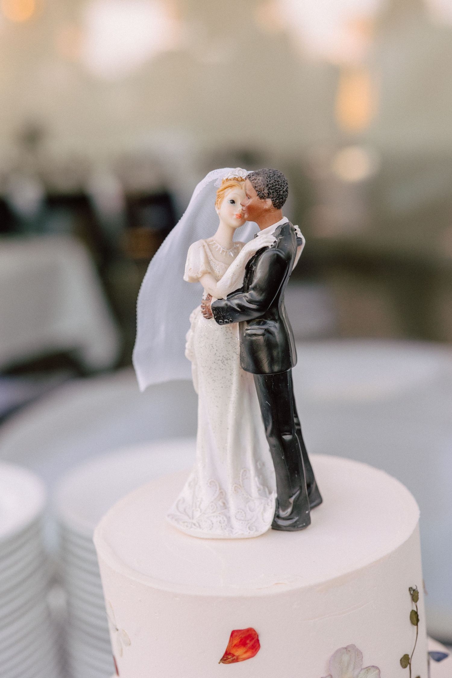 Wedding cake topper figurine of couple dancing on white frosted tier.