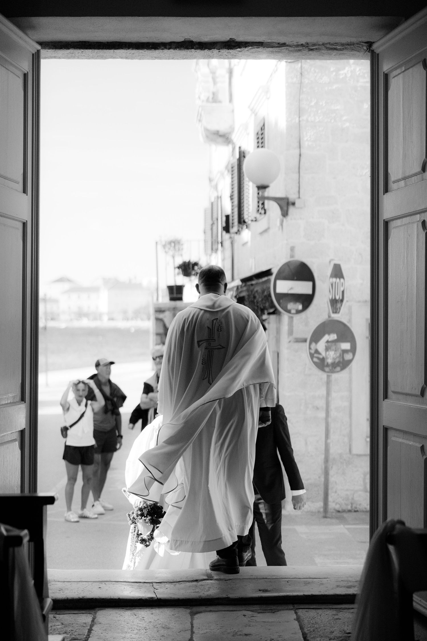 Black and white wedding photo showing silhouettes of guests mingling in a reception venue.