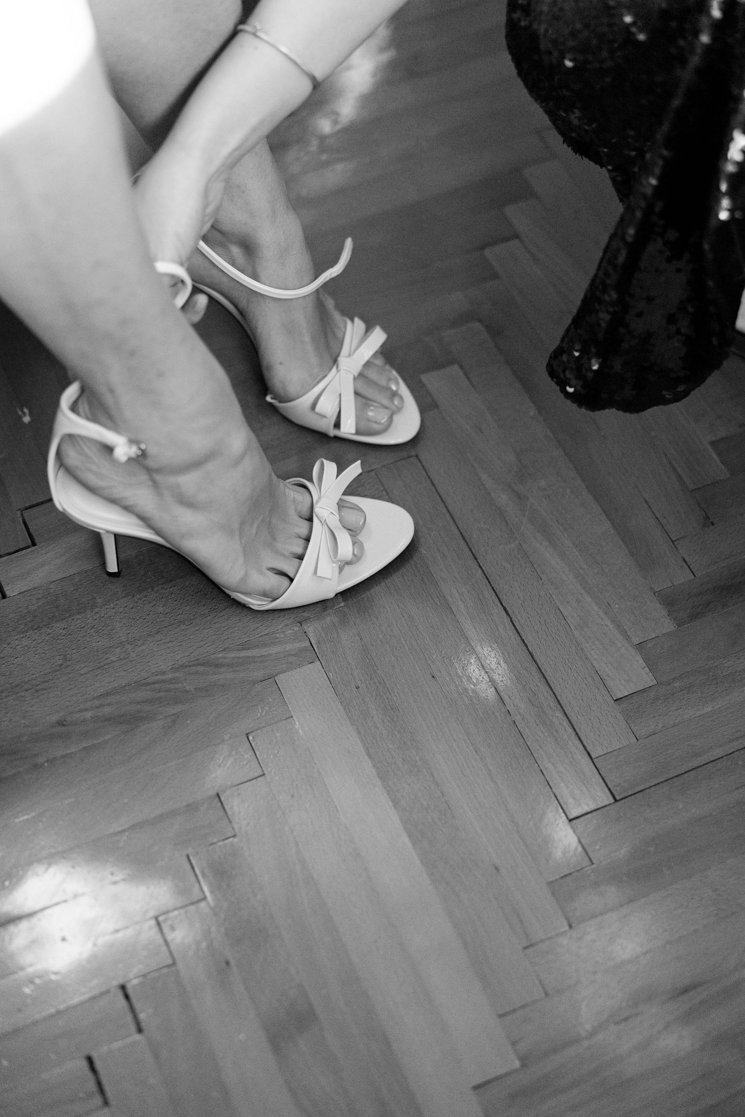 Close-up of white bridal heels on a wooden parquet floor.