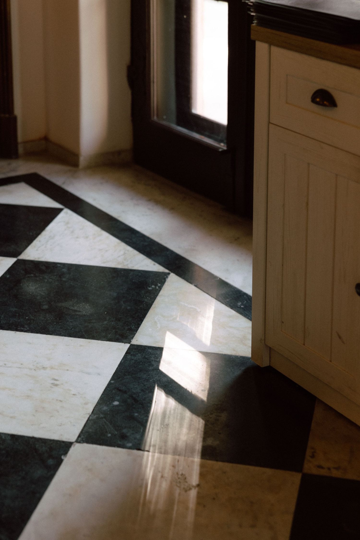Dramatic sunlight streaming across black and white checkered floor tiles.