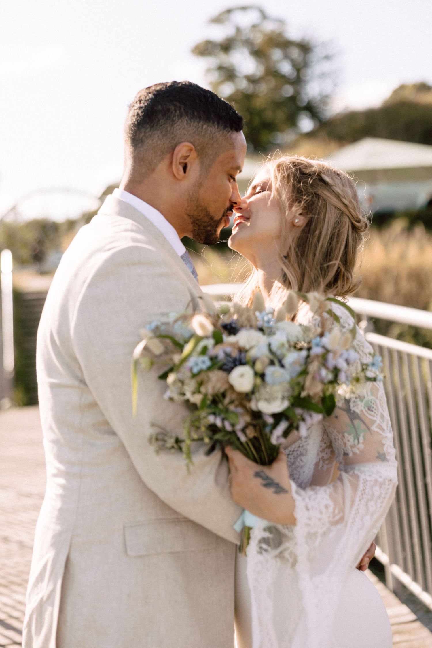 Intimate moment between newlyweds sharing laughter while holding wedding bouquet.