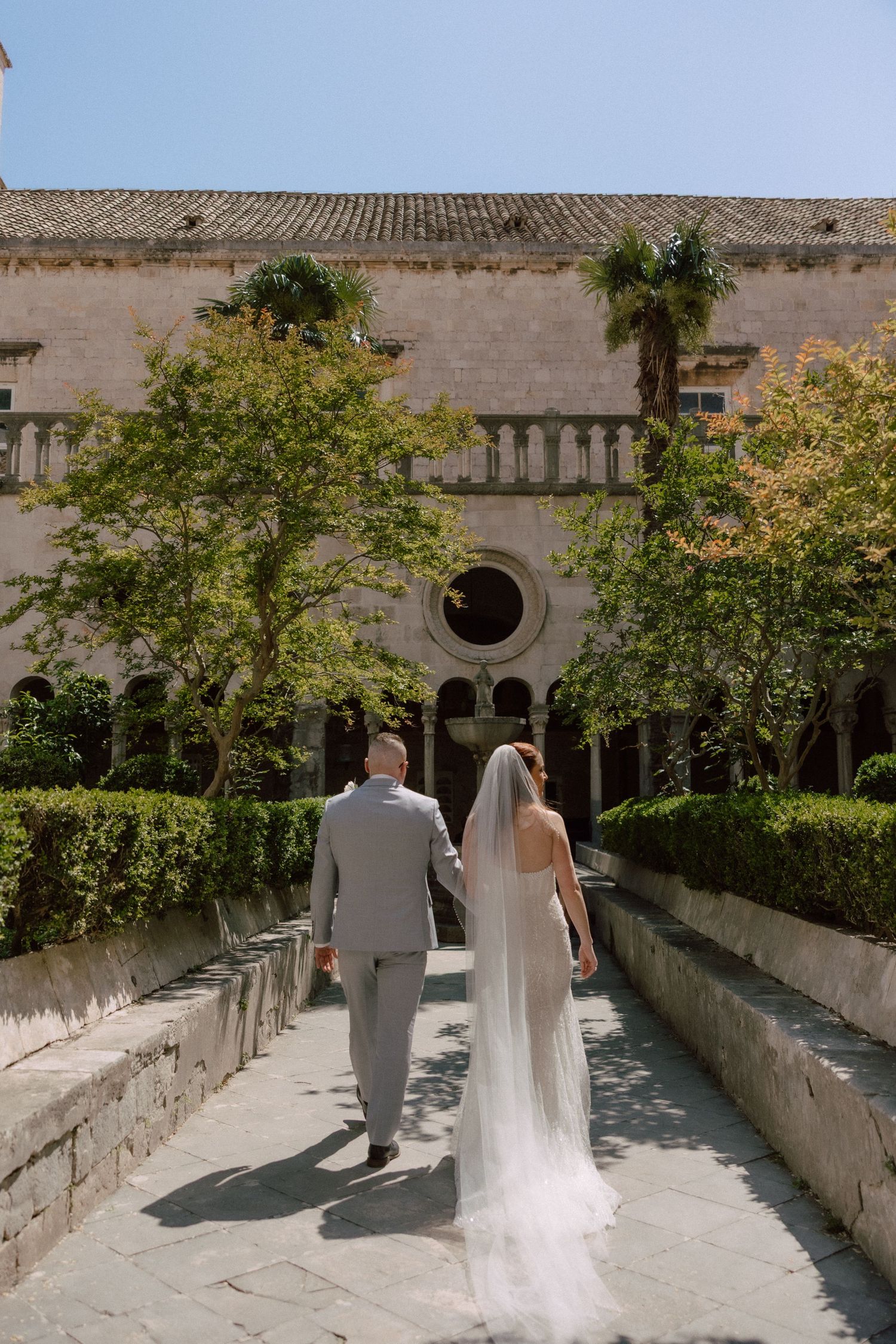 Elegant wedding photos in a Mediterranean courtyard with stone architecture and trees  in Dubrovnik, Croatia.