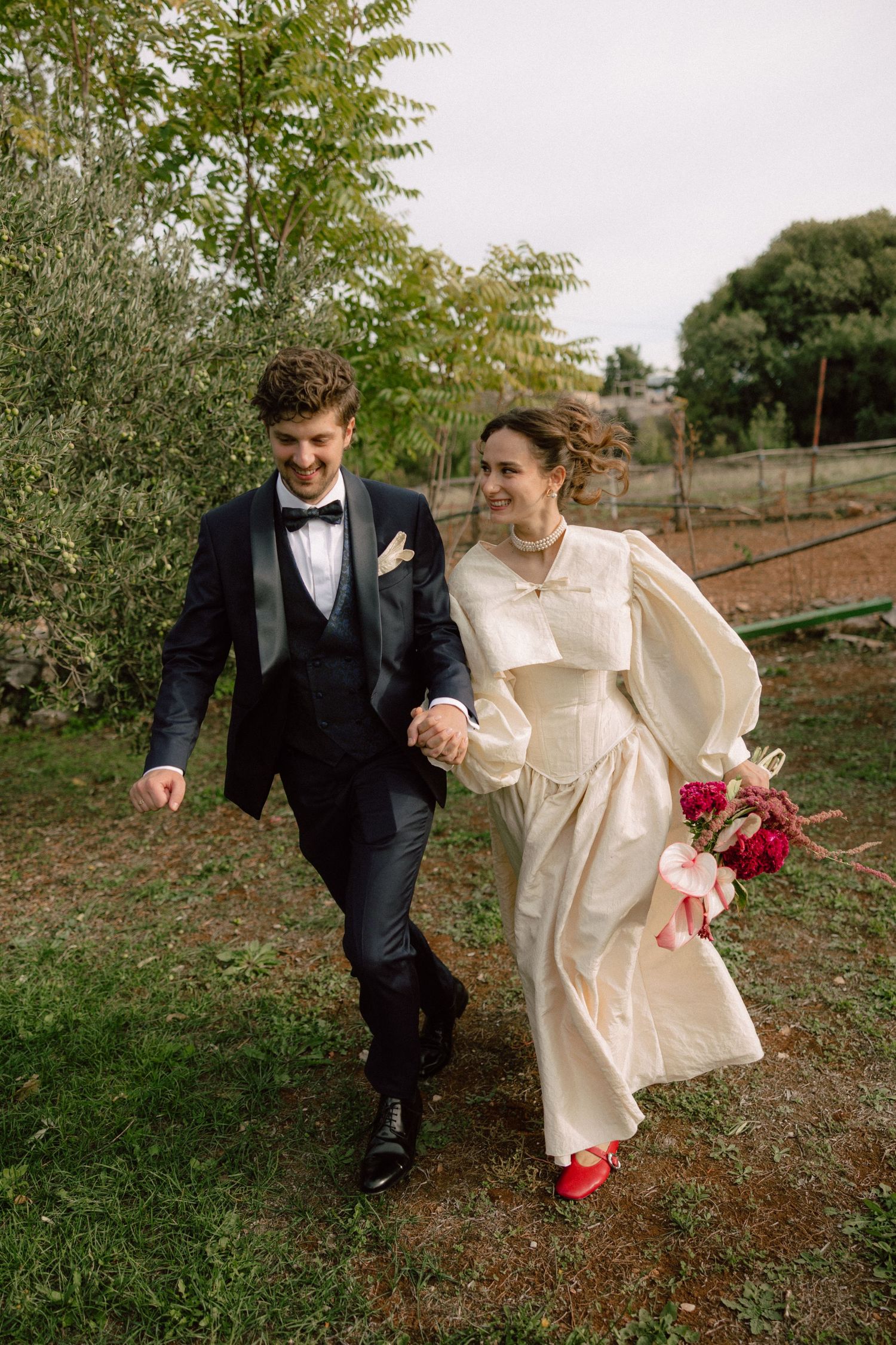 Couple walking together on grass path wearing formal wedding attire.