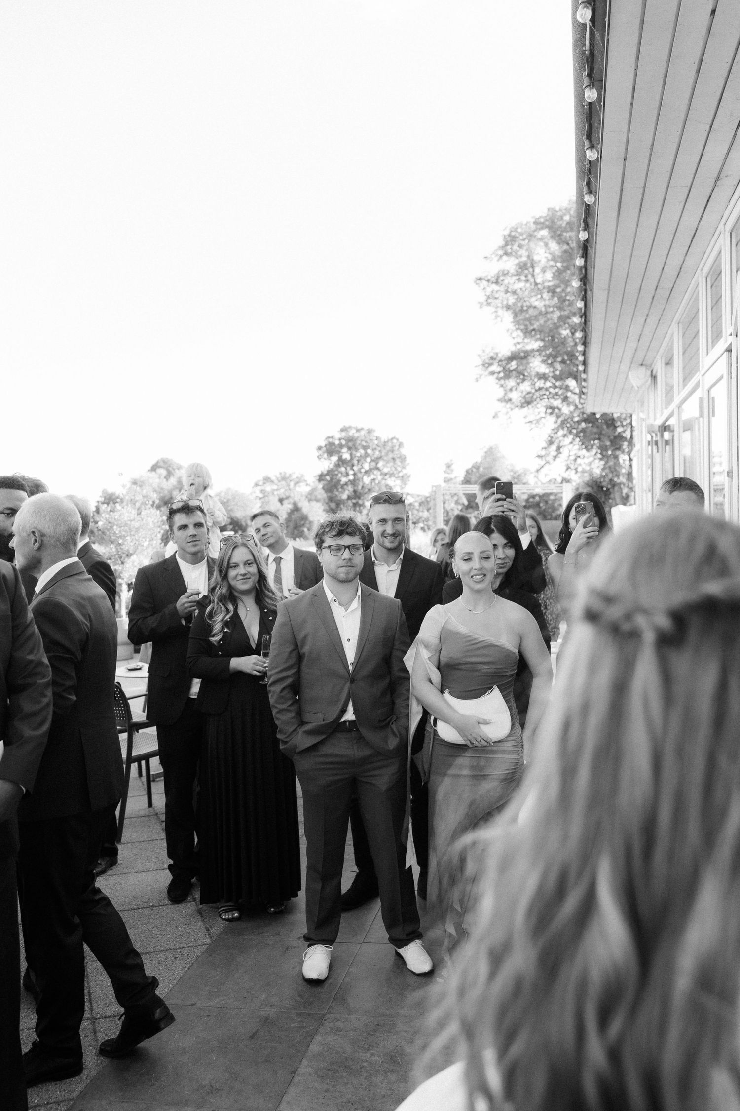 Wedding guests gather on outdoor patio during black and white reception celebration.