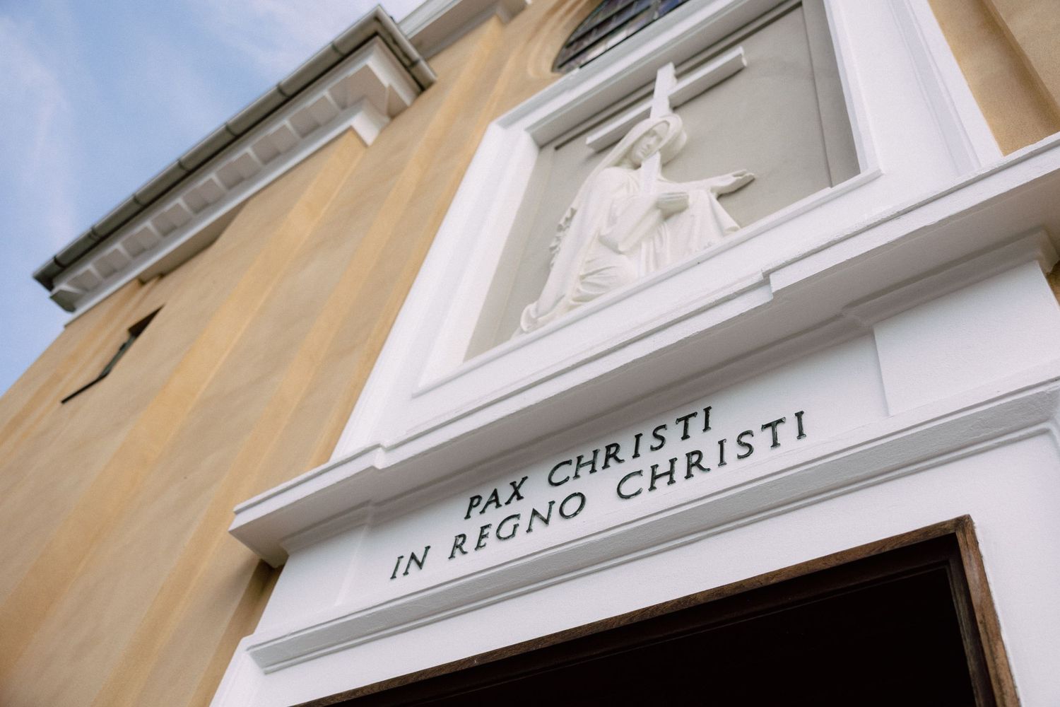 Ornate white architectural details and text on a beige building facade.