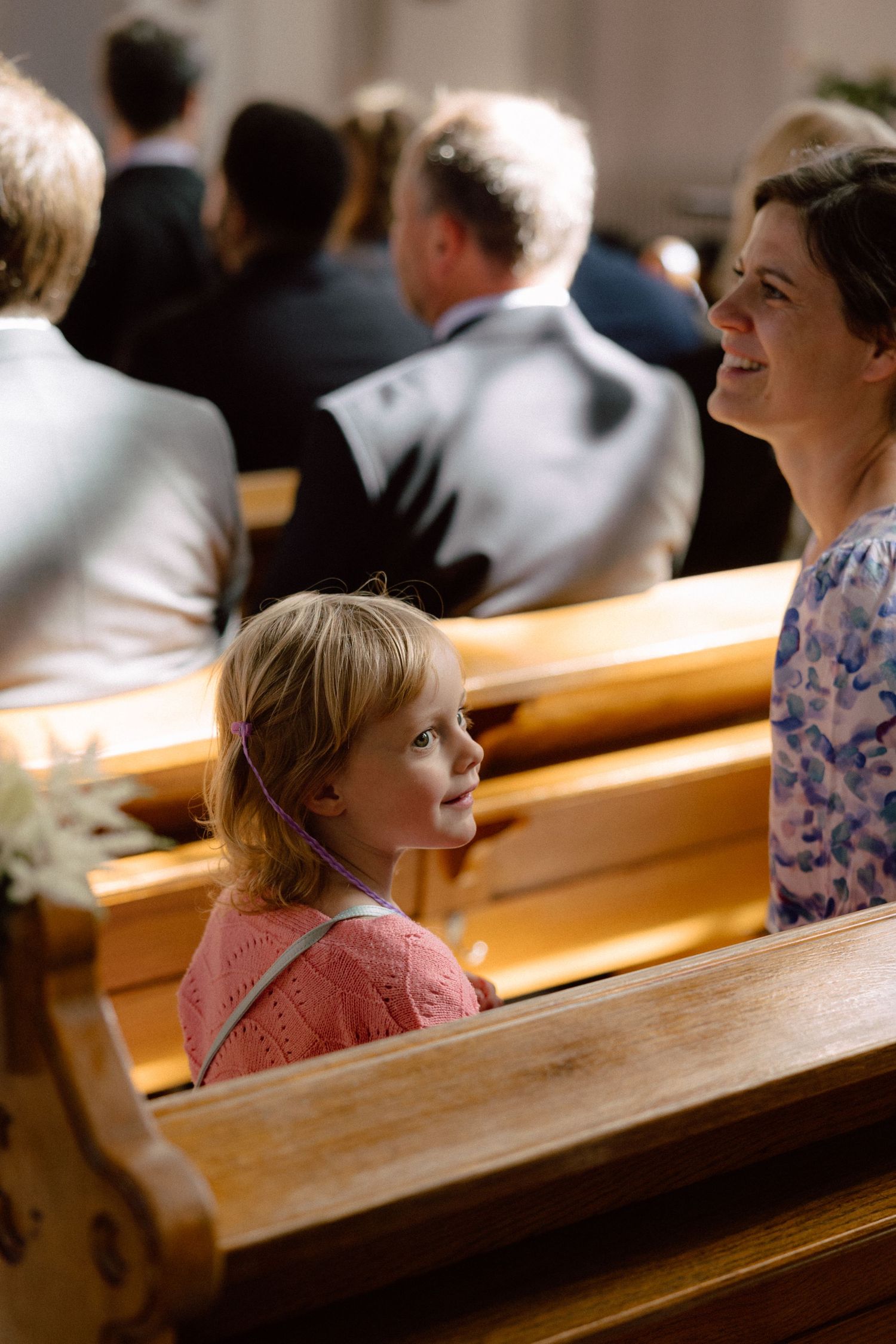 Wooden church pews filled with wedding guests during a ceremony.