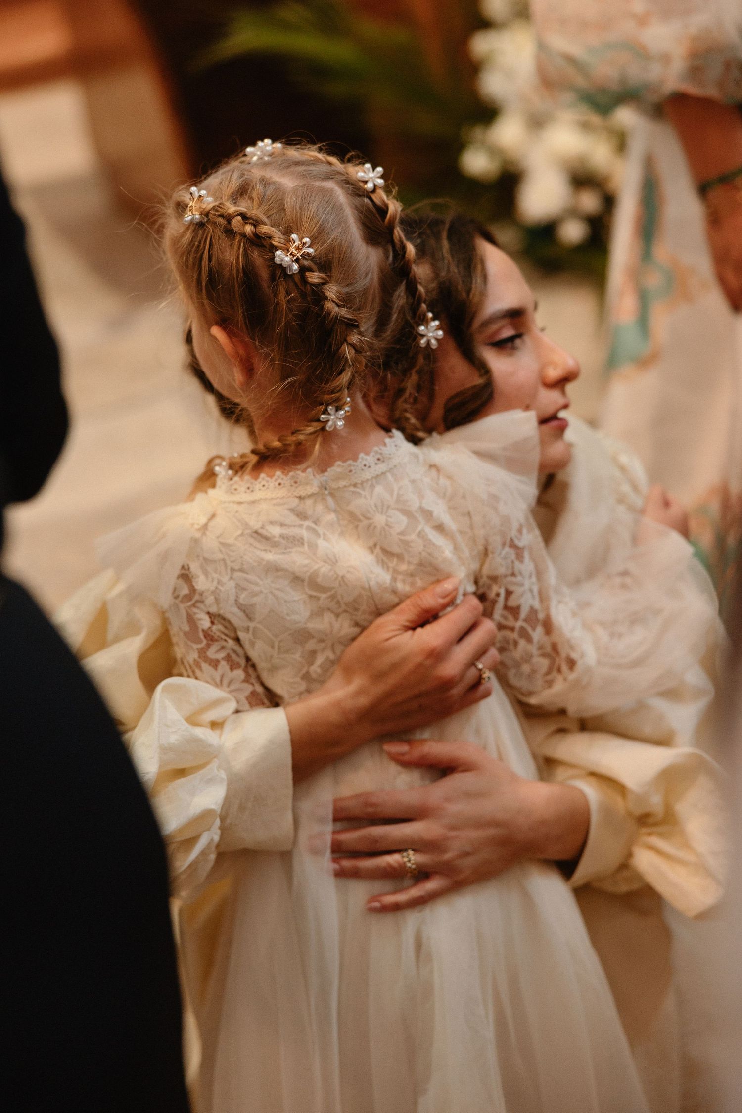 Tender embrace captured between two people in cream-colored formal attire.