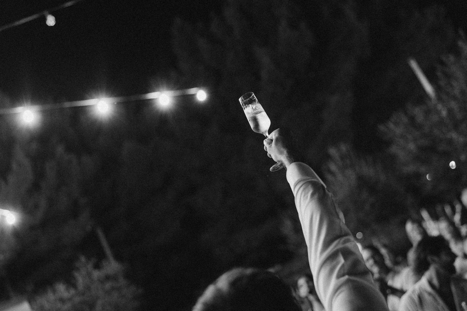 String lights illuminate an outdoor wedding reception space at night.
