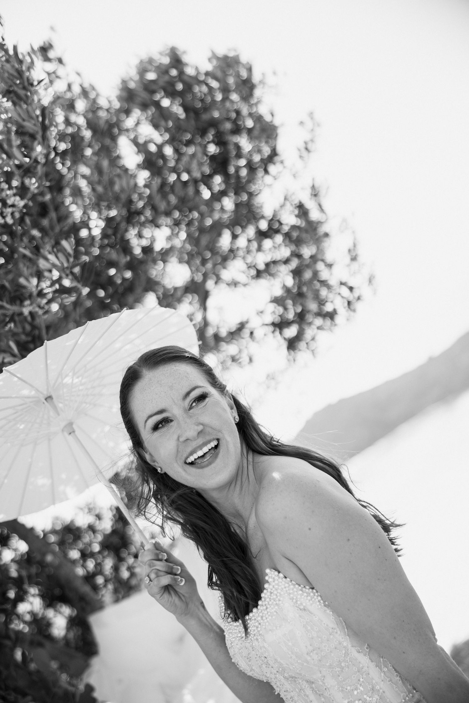 A joyful bridal portrait with parasol captured in black and white photography.