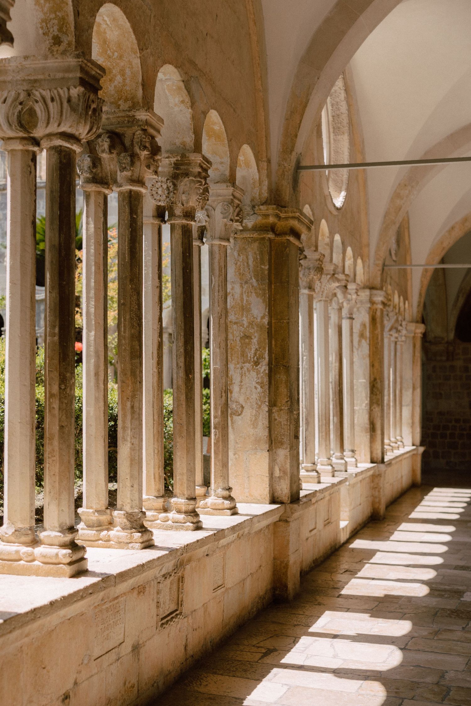 Ancient stone colonnade with arched walkway casting dramatic shadows through ornate pillars.
 in Dubrovnik, Croatia.
