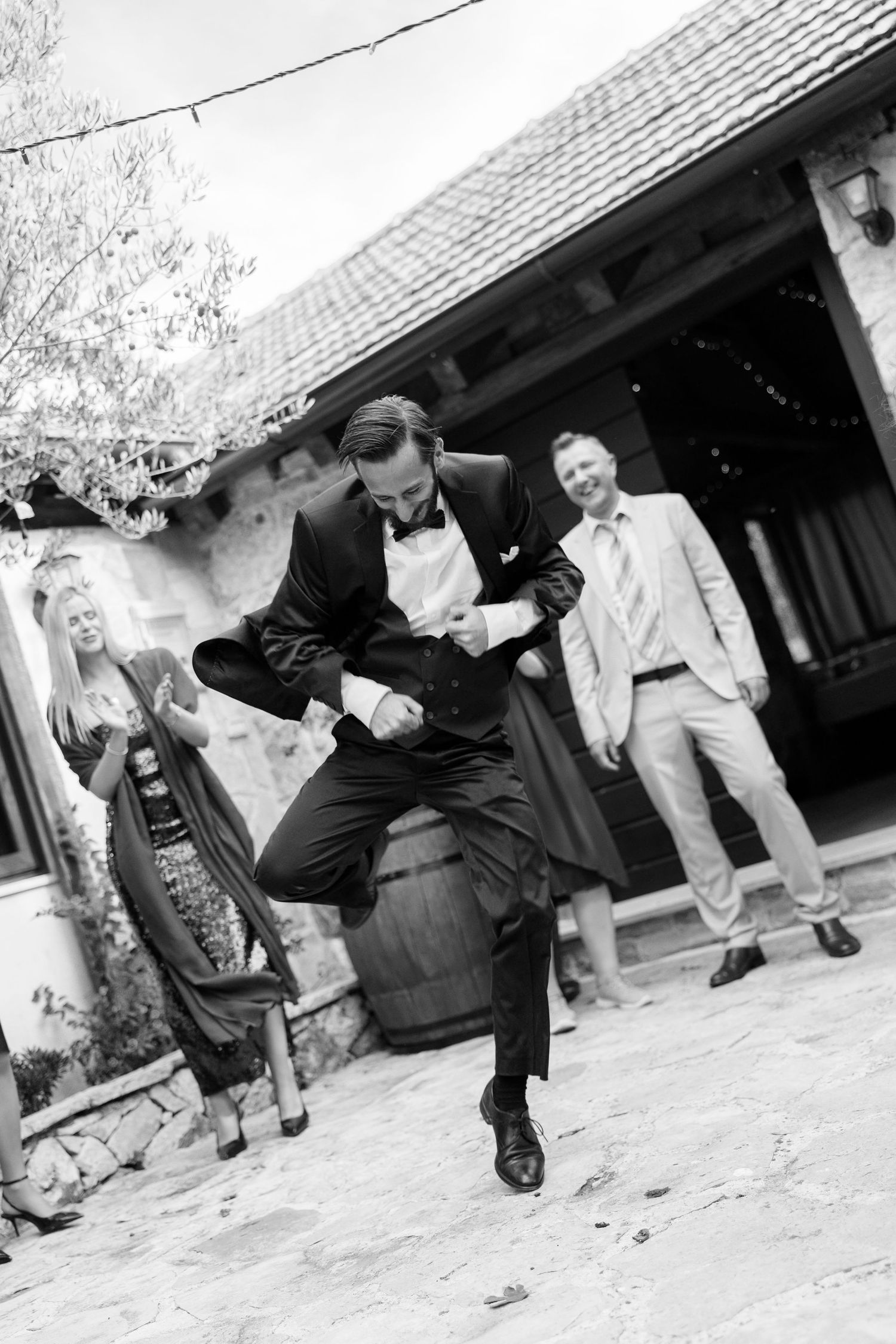 A joyful wedding guest dances energetically at an outdoor celebration.