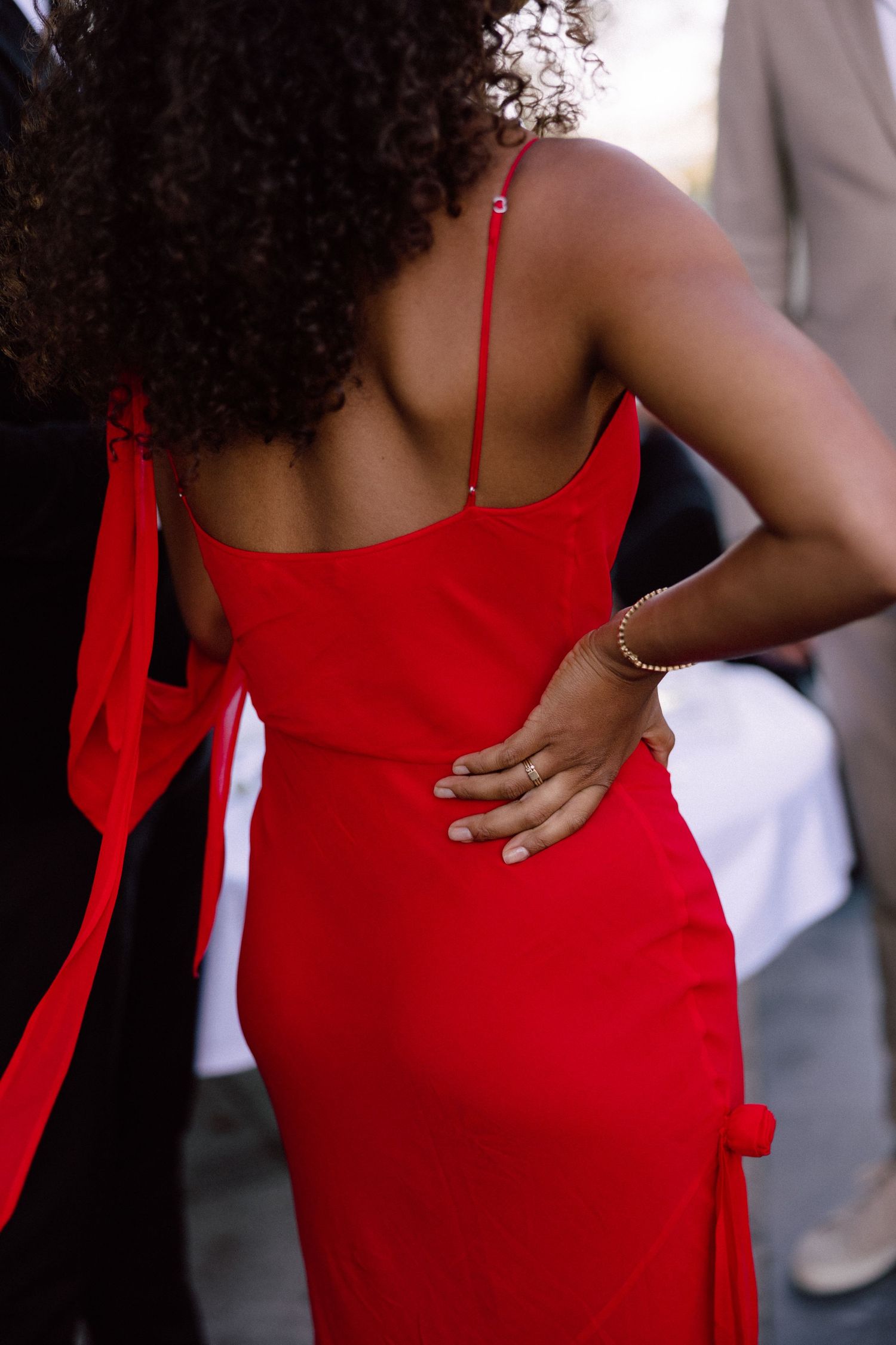 Back view of a woman in a striking red formal dress with curly hair.