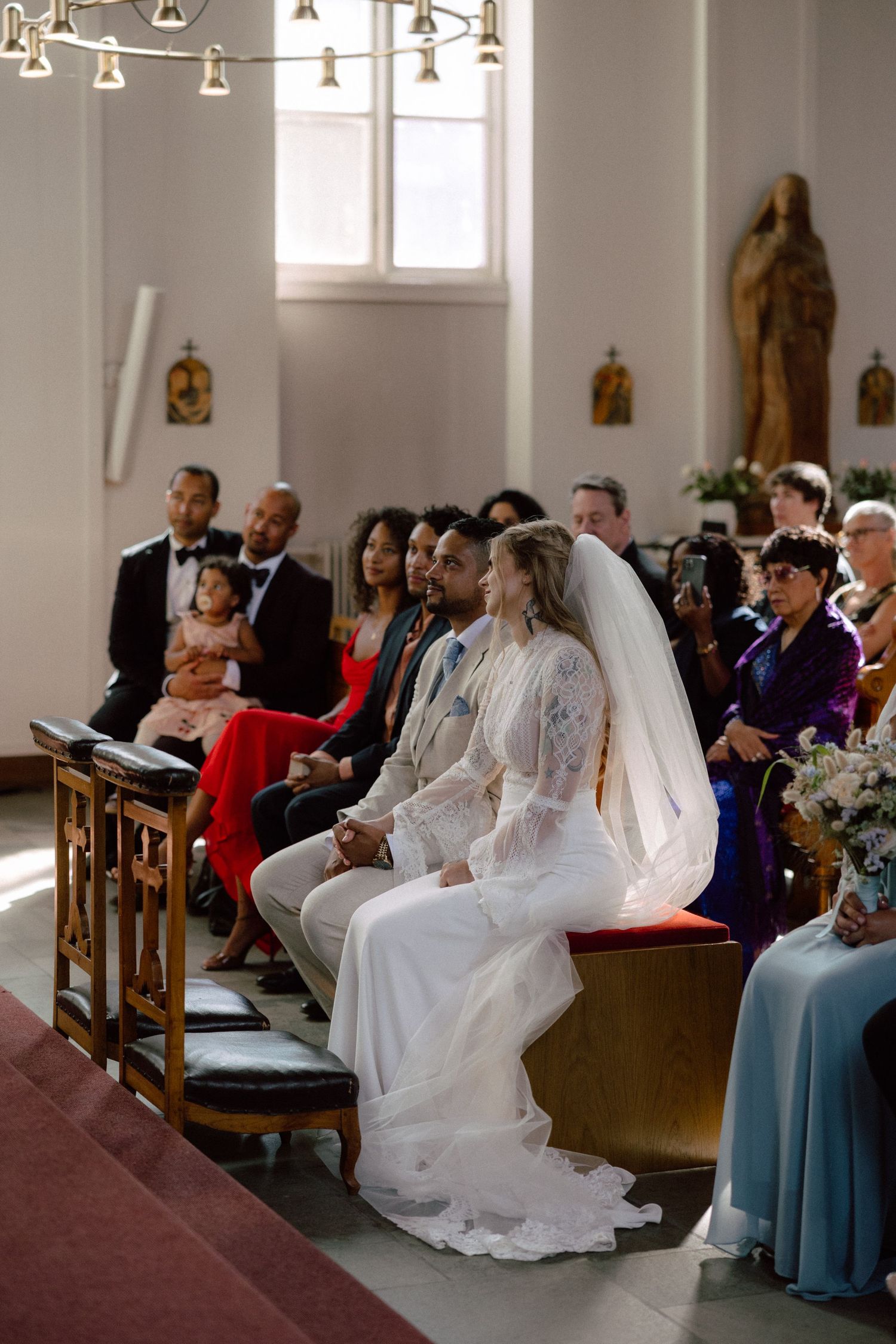 Wedding ceremony in progress with guests seated in traditional church pews.