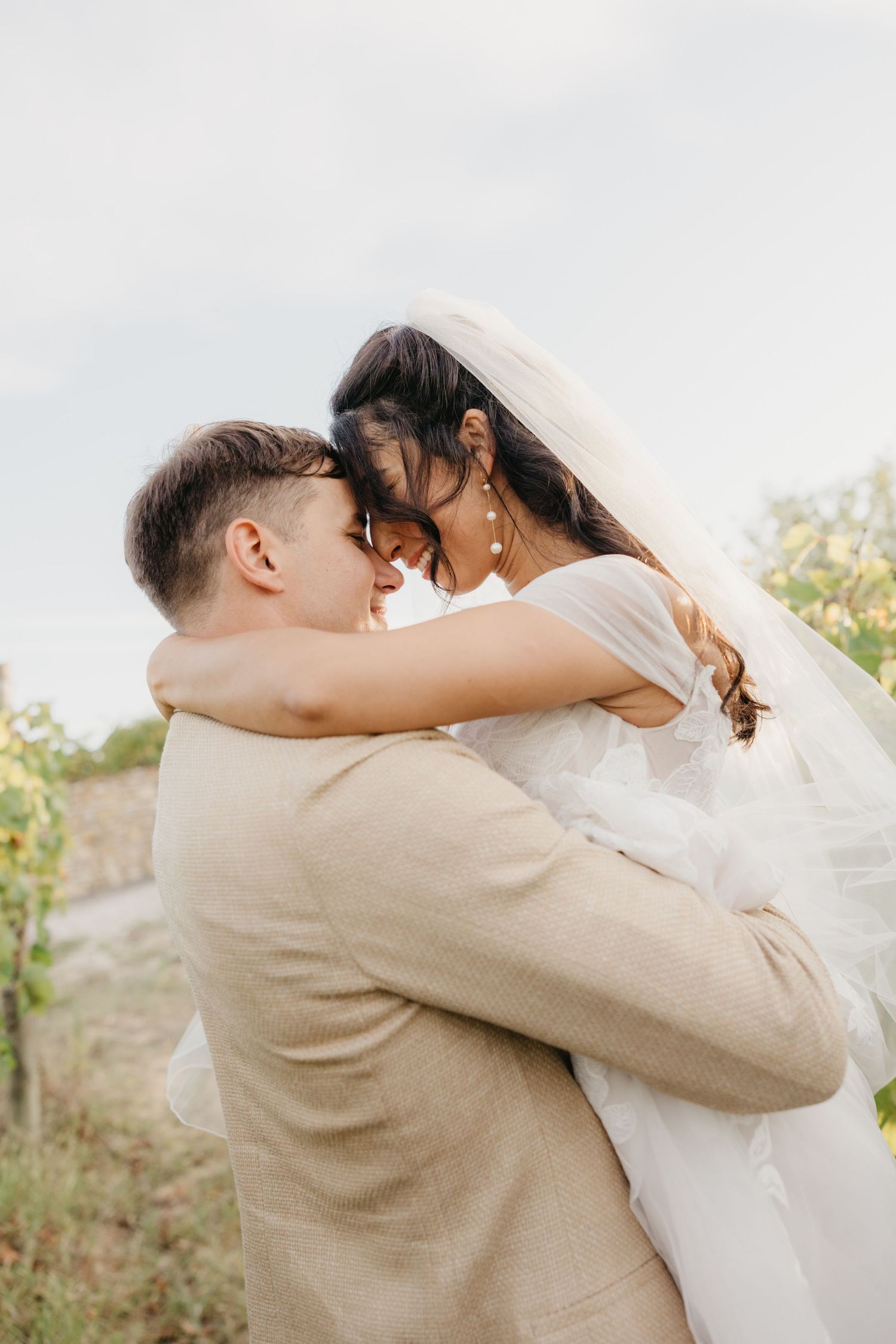 Romantic couple shares tender moments in beige and white wedding attire.