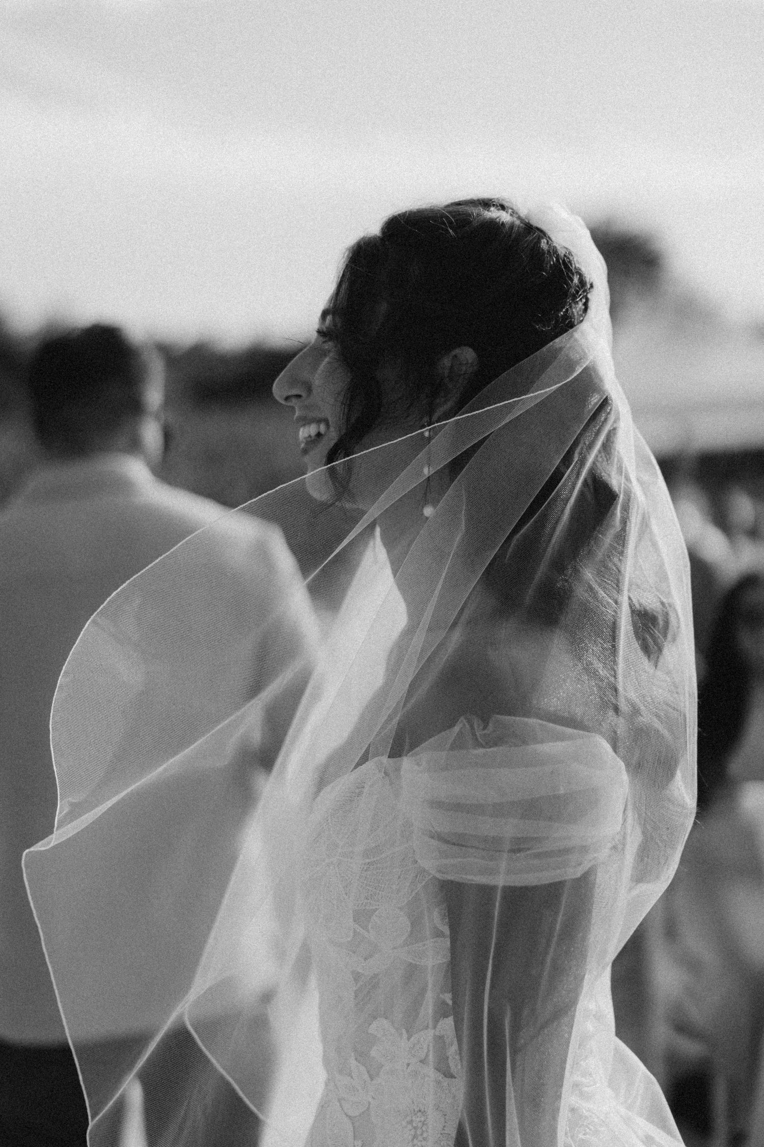 Close-up side profile of bride wearing delicate white veil in black and white.