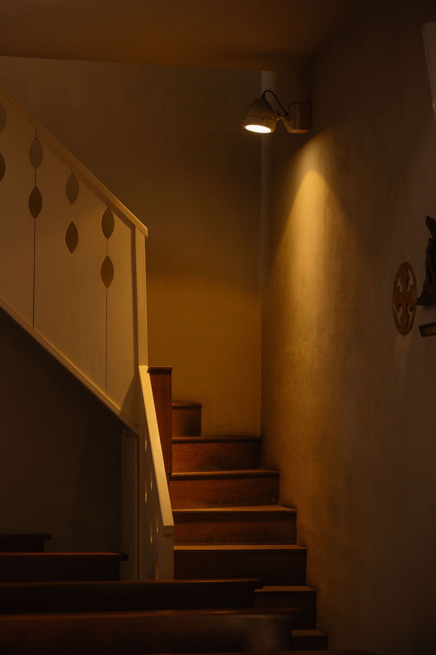 Dimly lit wooden staircase with dramatic shadows and warm lighting.